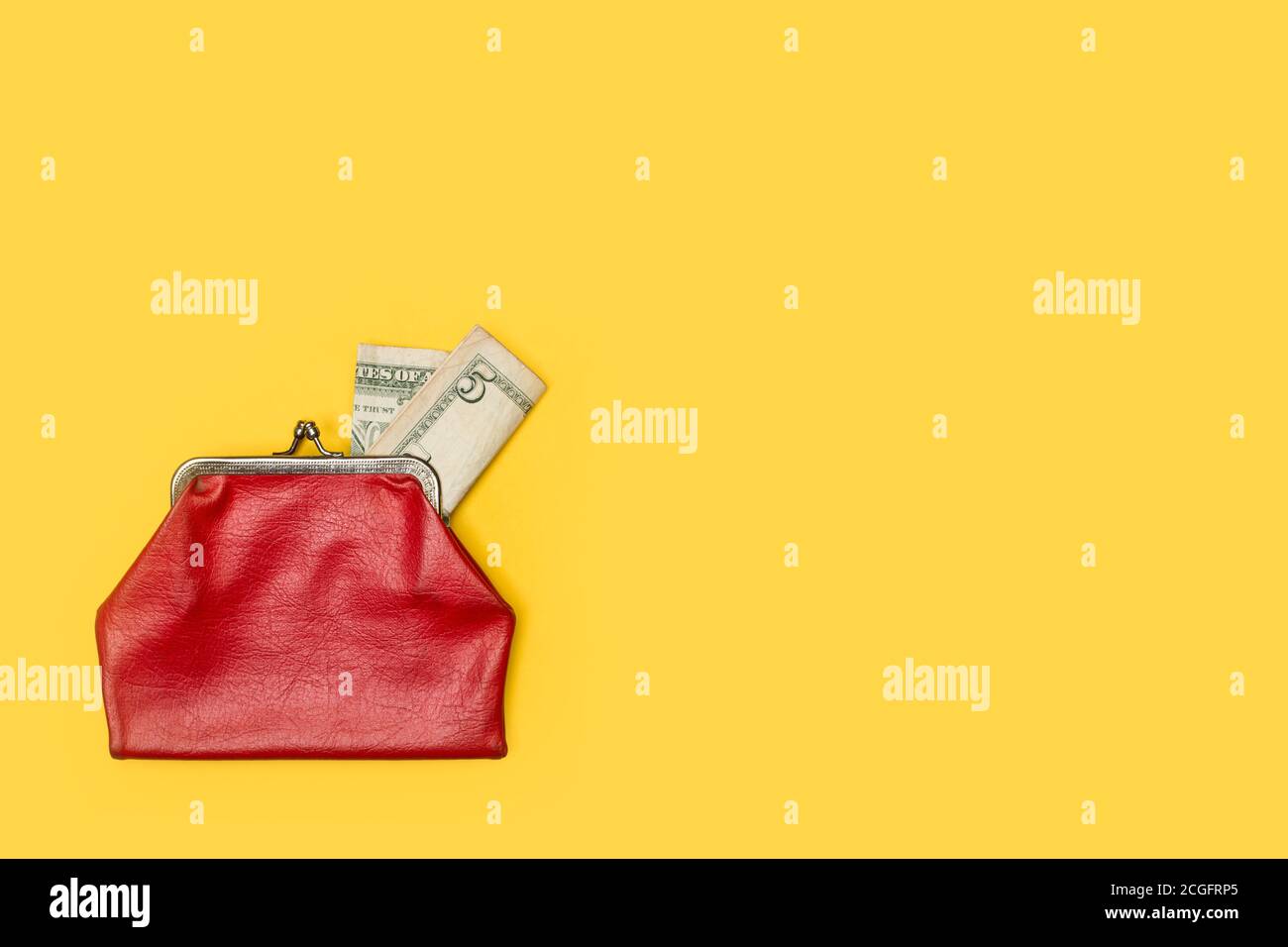 Old red coin purse with a five dollar note on a yellow background Stock Photo