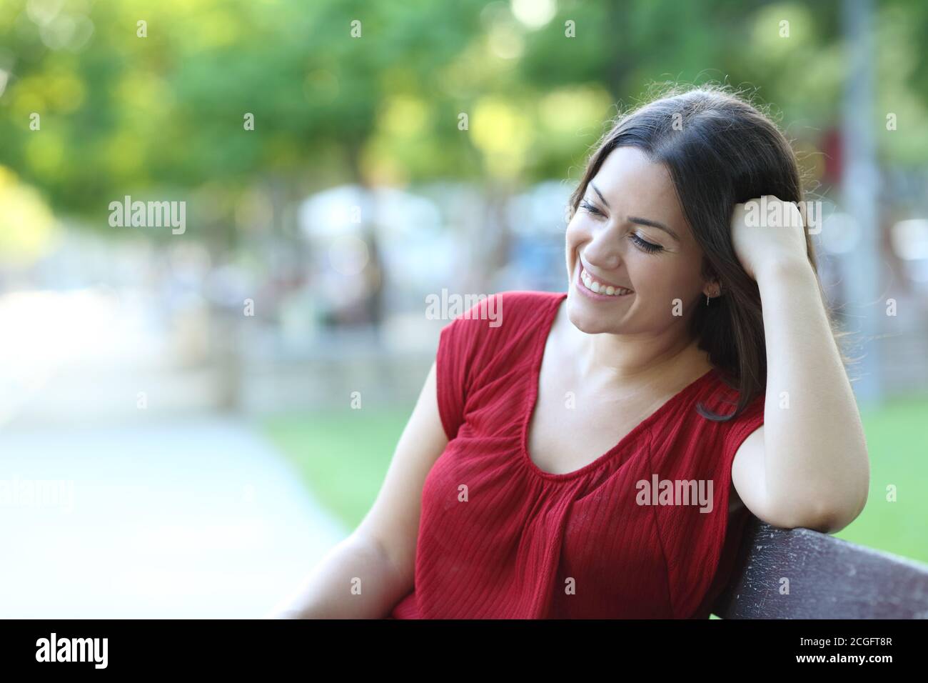 Happy woman relaxing contemplating sitting on a bench in a park Stock Photo