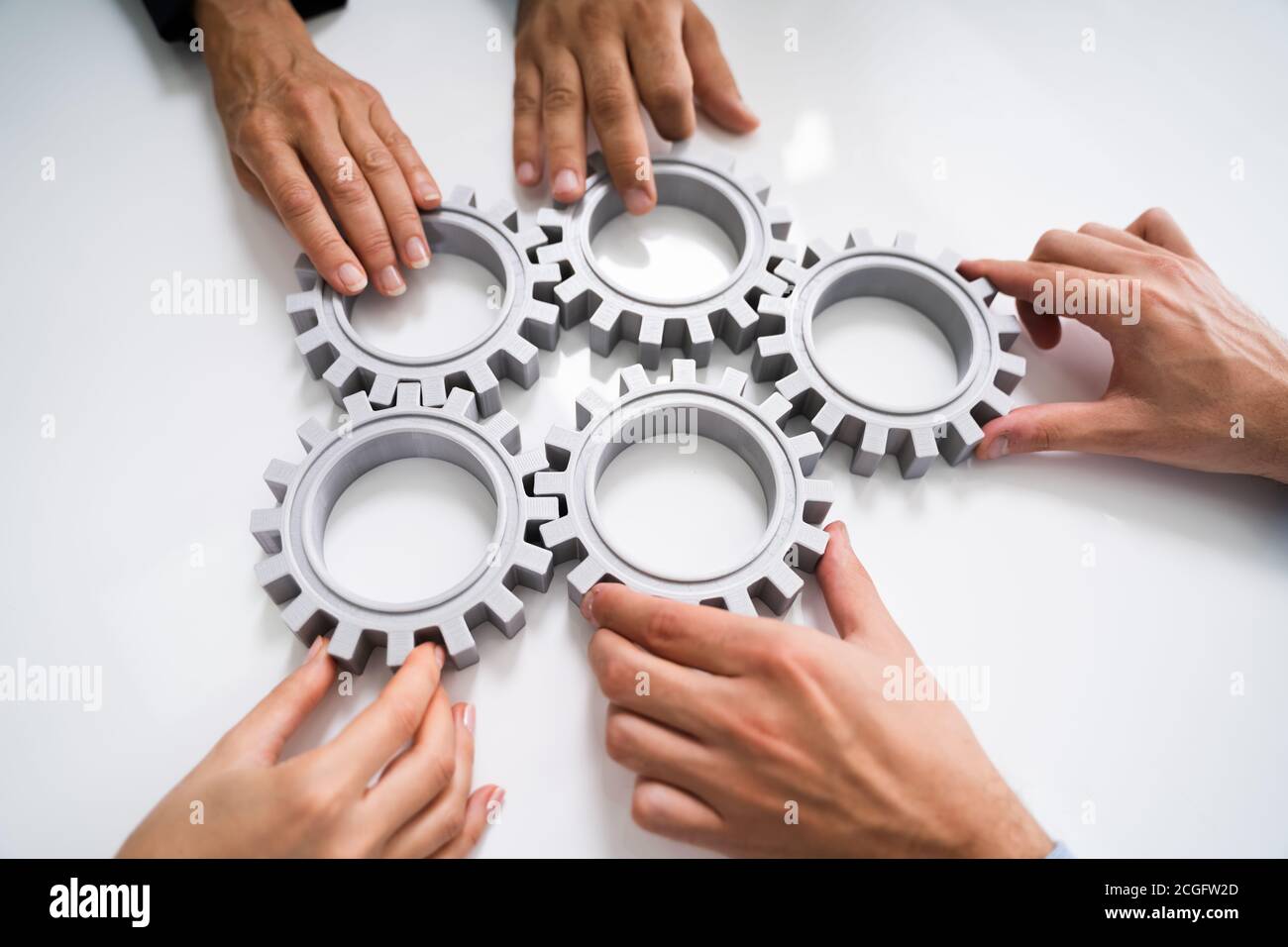 Innovative Businesspeople Team Hands Joining Gears At Desk Stock Photo