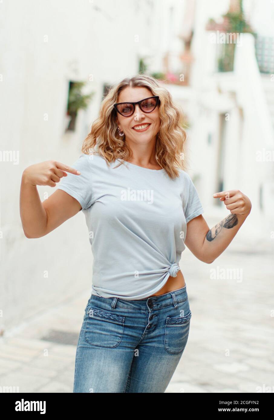 Young women wearing tshirt and jeans point to the center of a tshirt