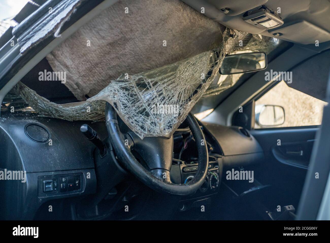 Completely destroyed car. The windshield is broken and lies inside the car Stock Photo