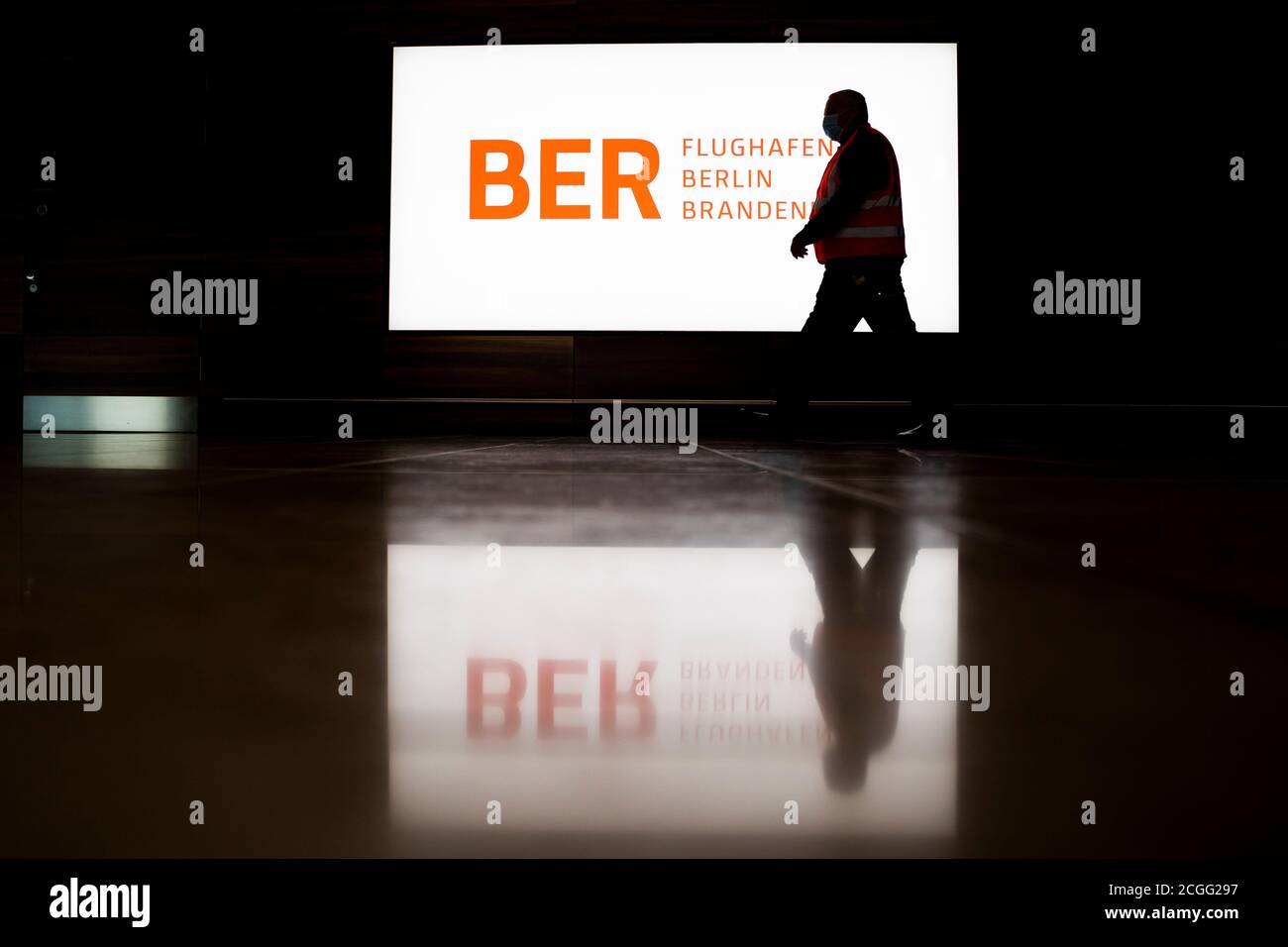 08 September 2020, Brandenburg, Schönefeld: A man walks "Willy Brandt" (BER) in front of an illuminated banner with the BER logo during a tour of the capital airport Berlin Brandenburg. The Capital Airport is scheduled to open on 31 October 2020. Photo: Christoph Soeder/dpa Stock Photo