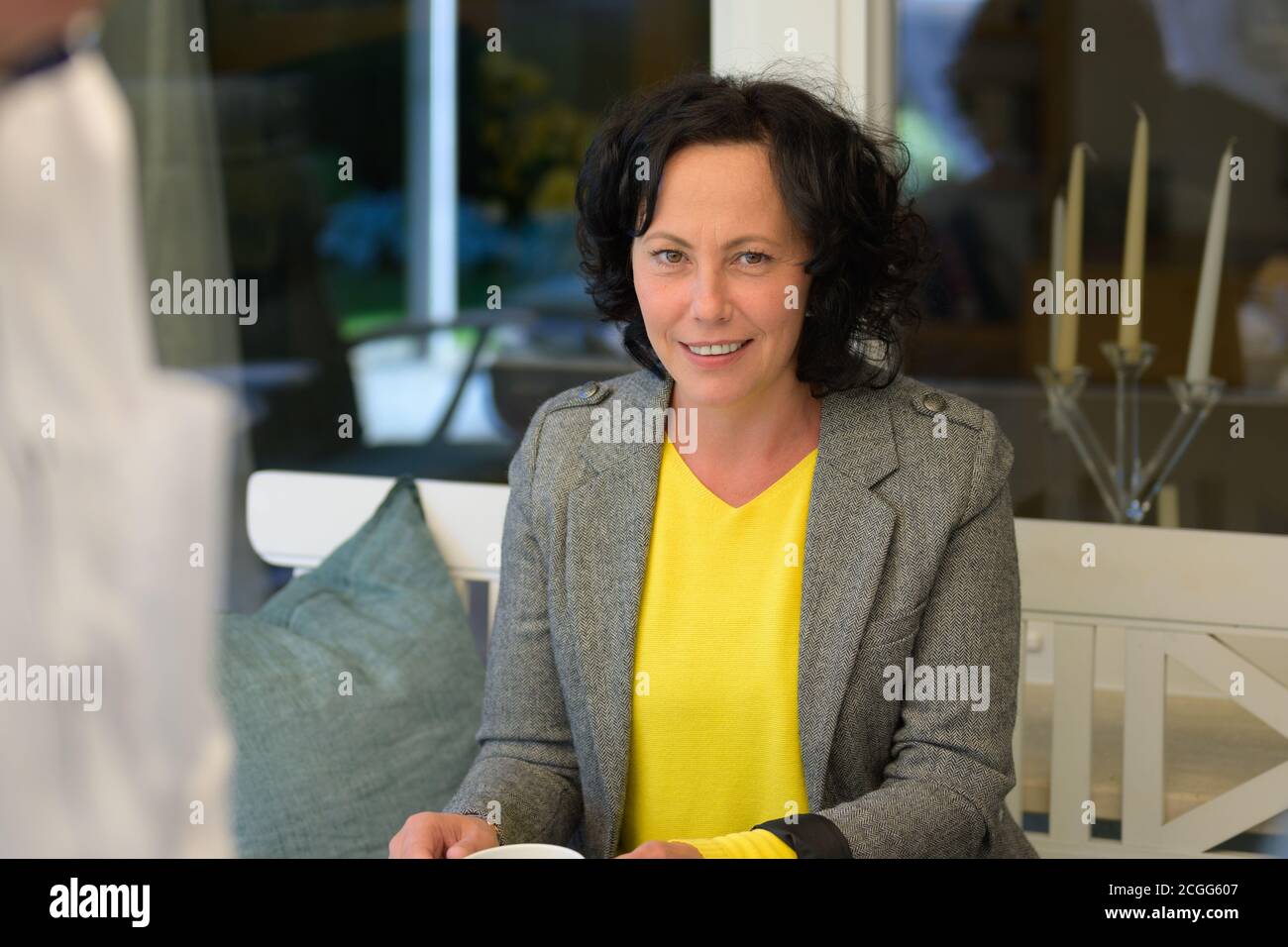 Happy middle-aged Hispanic woman with a vivacious smile drinking coffee Stock Photo