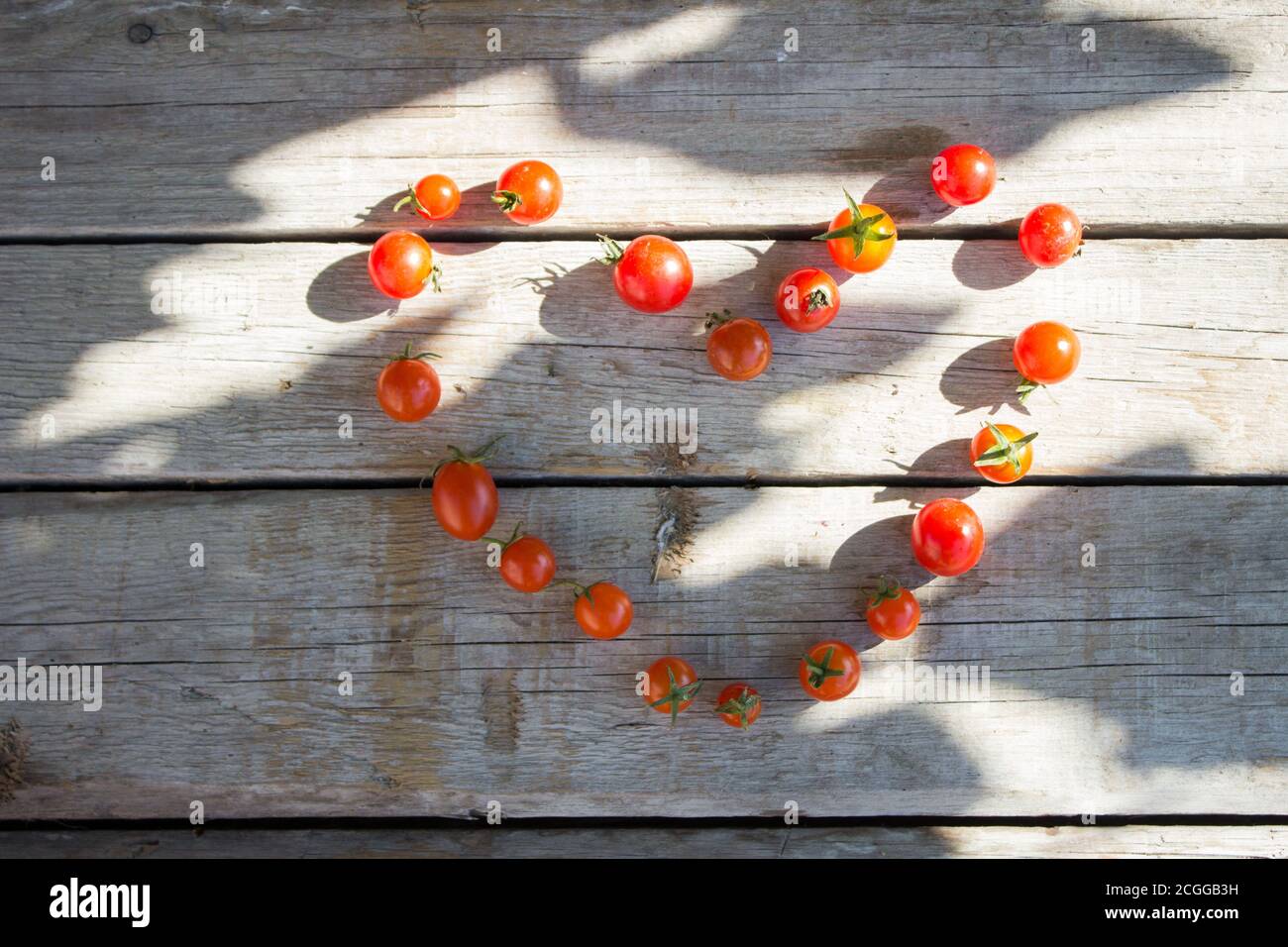 Small cherry tomato, tomatoes on a wooden background lined in the shape of a heart Stock Photo