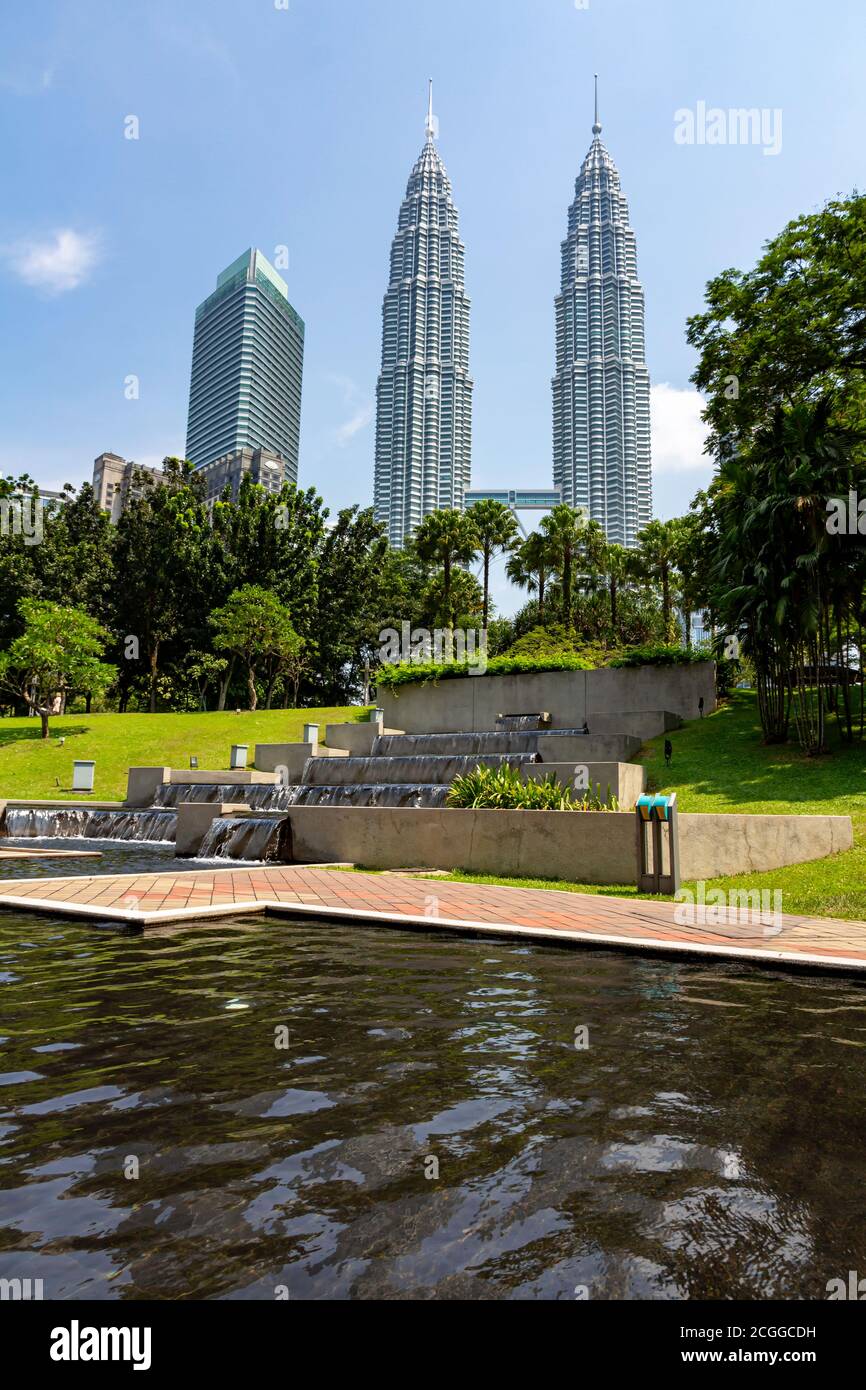 KUALA LUMPUR, 17 August 2013 - The Petronas, twin towers emerge from the KLCC garden skyline under a hash cloudless summer sky, Malaysia Stock Photo