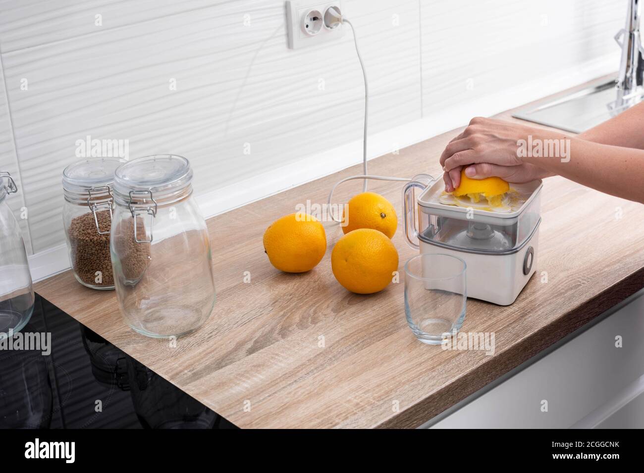 Woman squeezing oranges in the kitchen Stock Photo