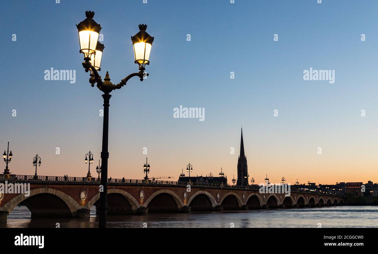 Street lights lit up at sunset, Pont de Pierre bridge  in the background, Bordeaux, France. Stock Photo