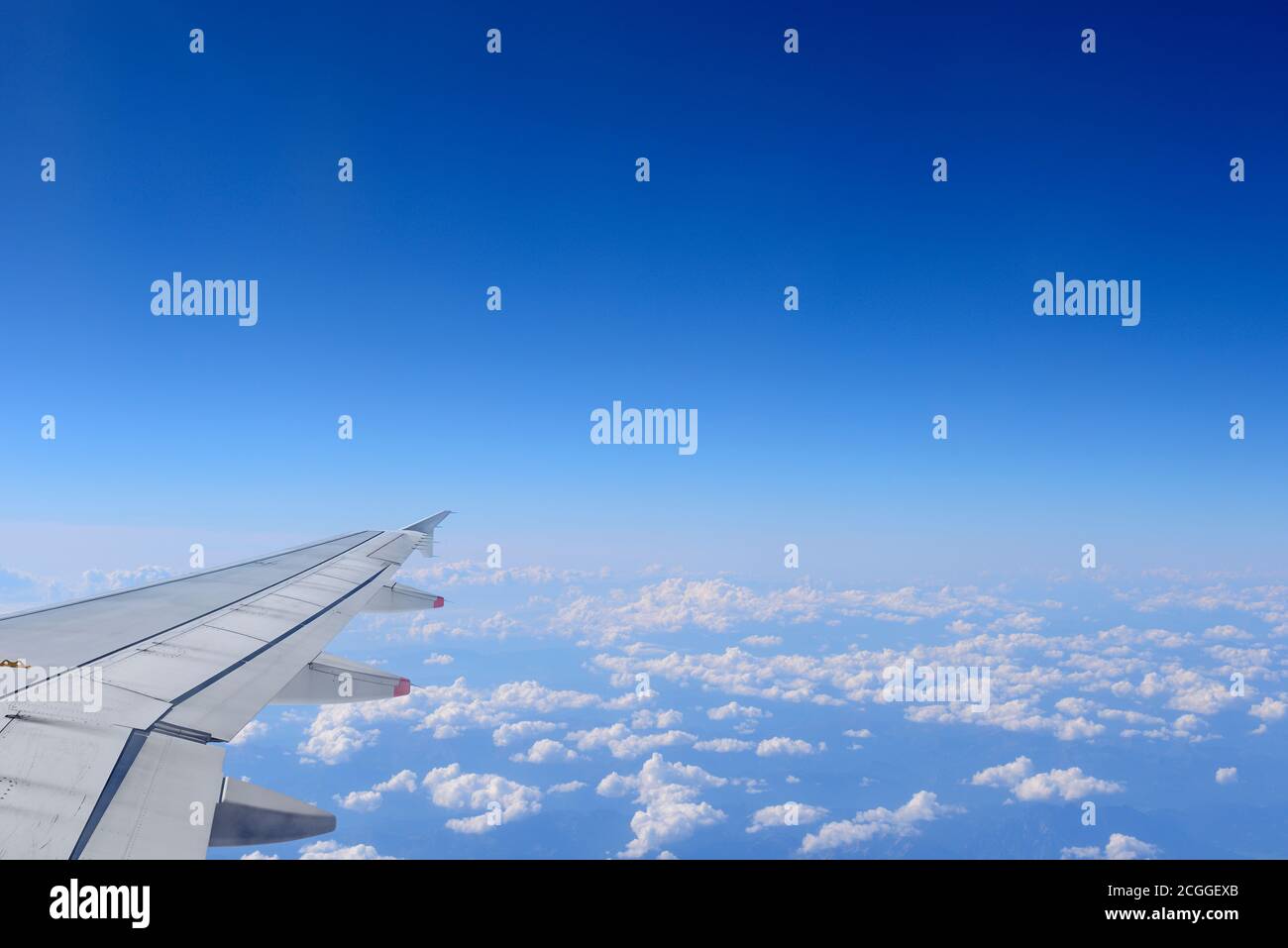 Airplane Wing Over a Bright Blue Sky Stock Photo