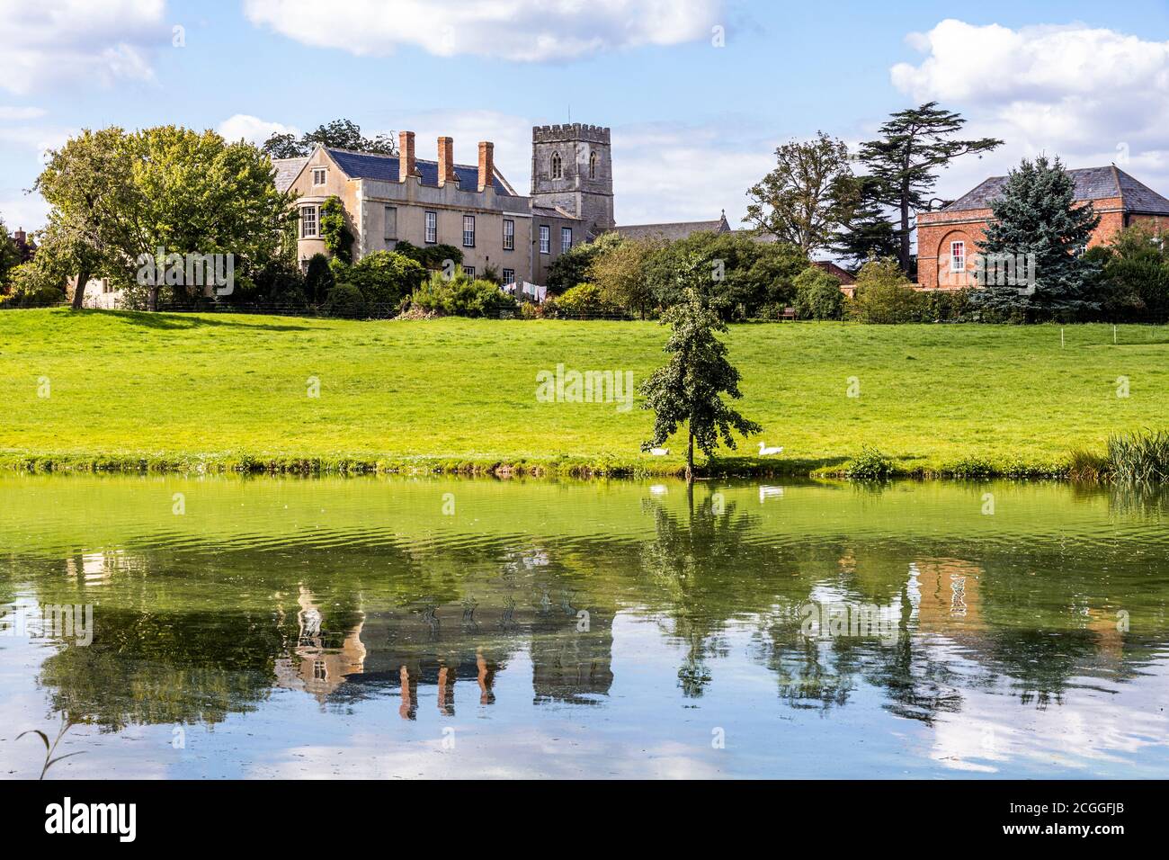 Maisemore Court and St Giles church viewed across the lake in the Severn Vale village of Maisemore, Gloucestershire UK Stock Photo