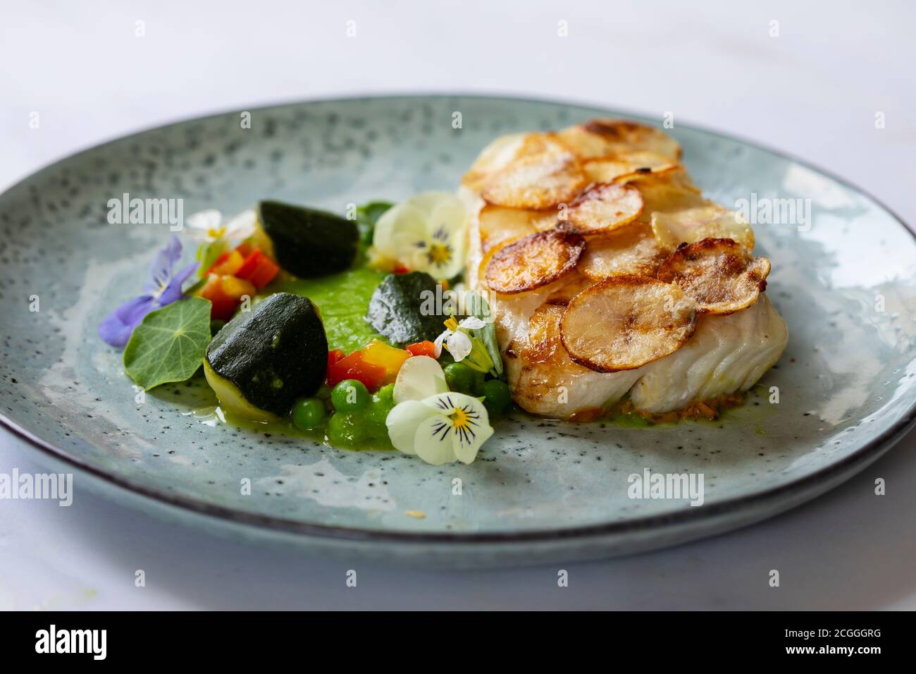 White fish fillet with potato scale, pea puree and summer vegetable ...