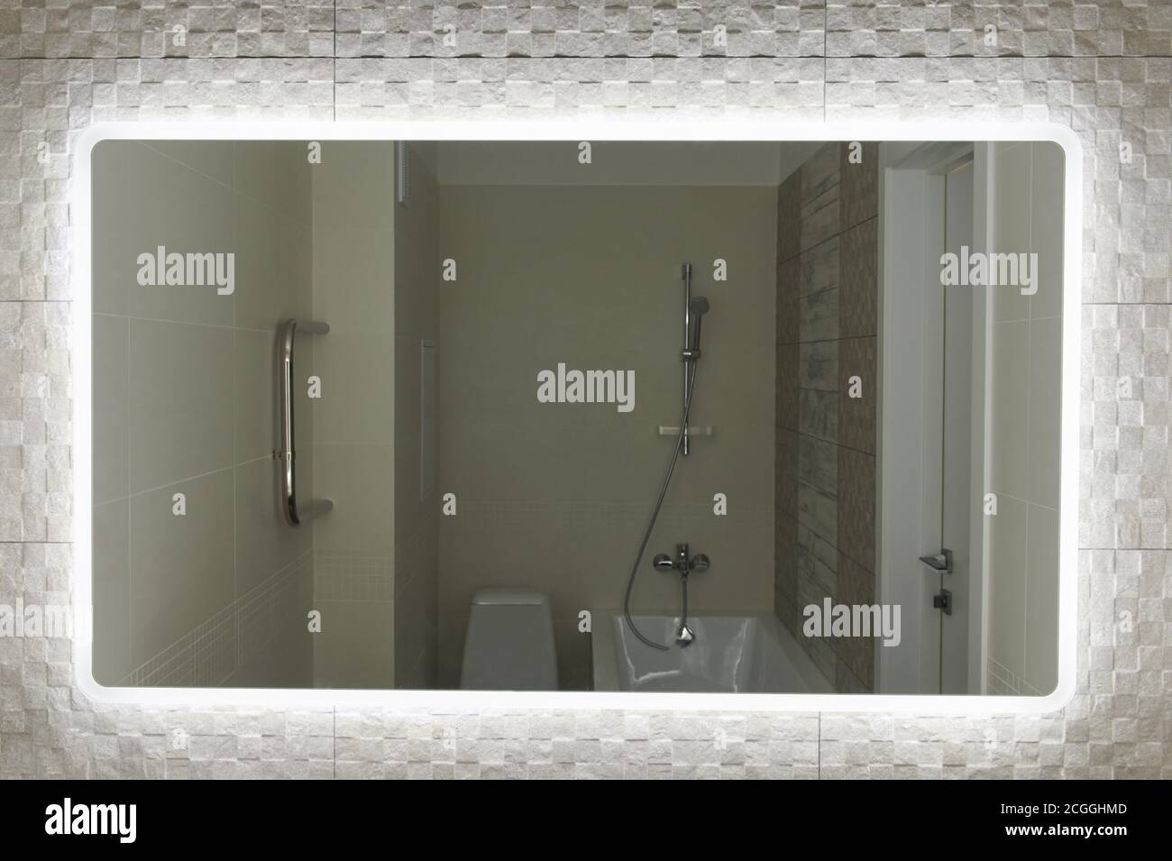 Wide big mirror in bathroom with illumination on tile background Stock Photo
