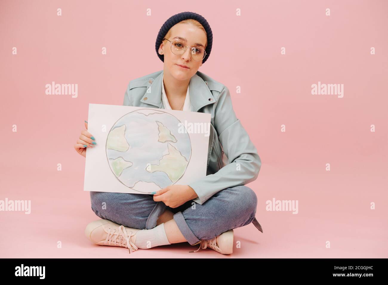 Cute Female Eco Activist In A Cap Sitting Cross legged With Earth Banner Stock Photo Alamy