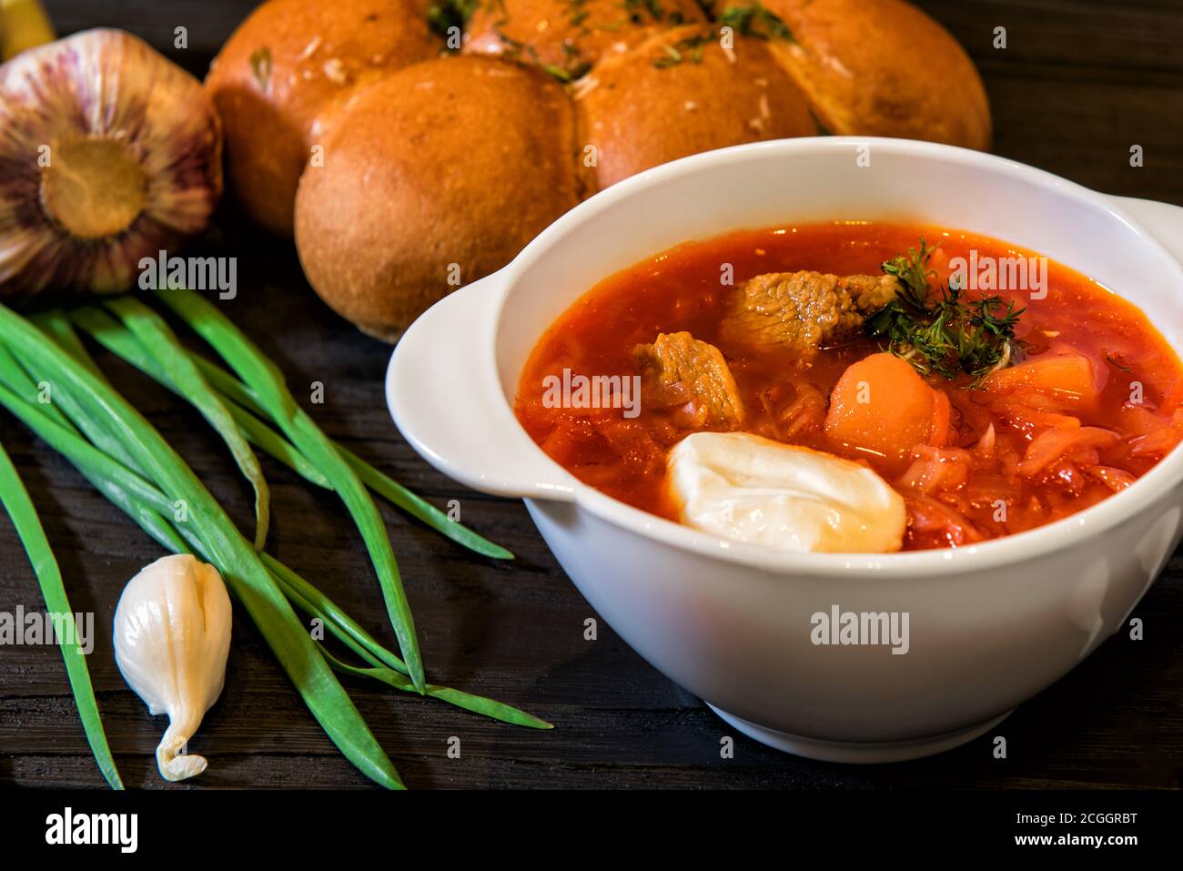 Traditional Ukrainian soup borscht / borsch with savory garlic bun pampushkas on the table among vegetables and spices Stock Photo