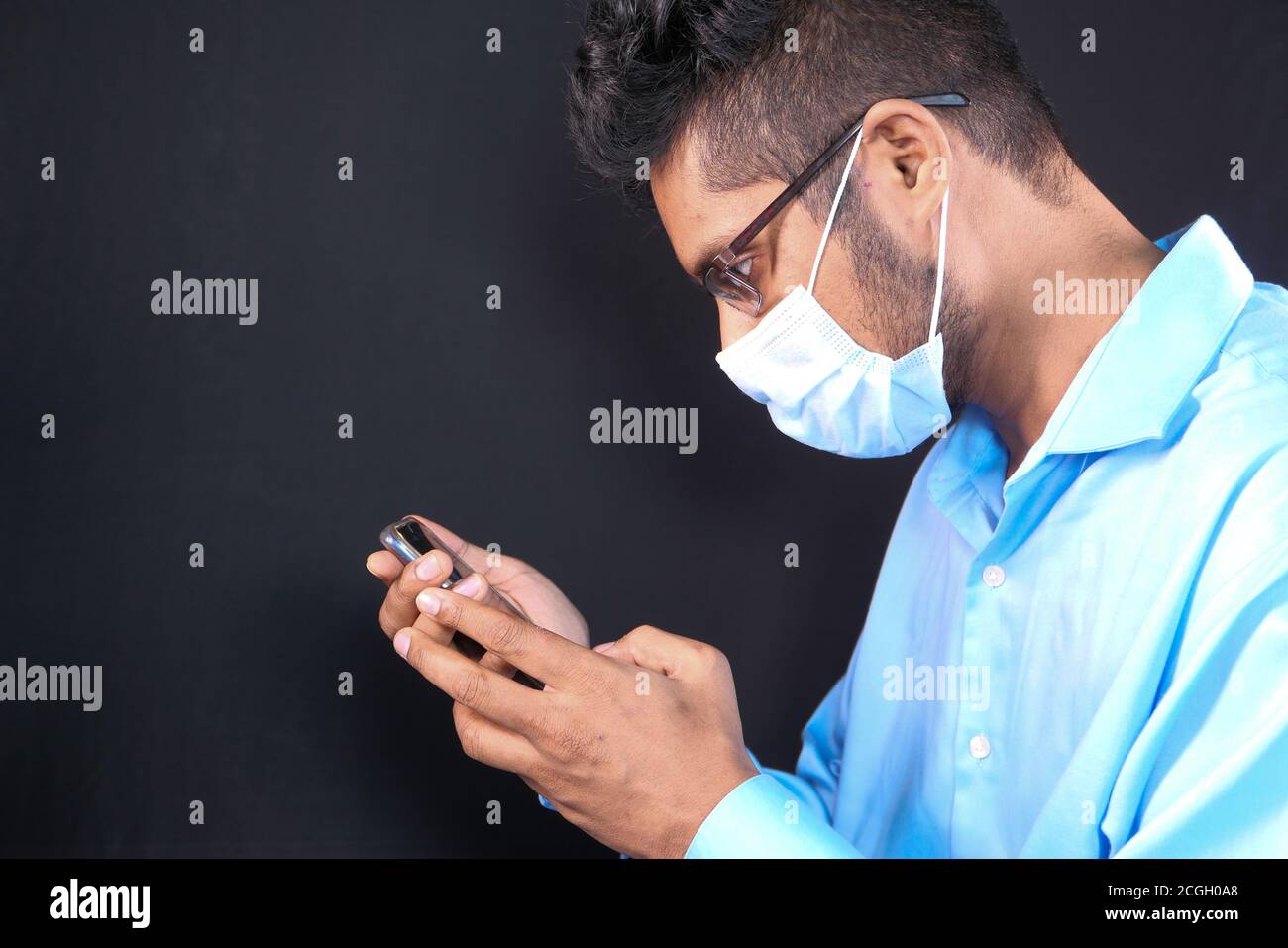 young man with face mask using smart phone indoor  Stock Photo
