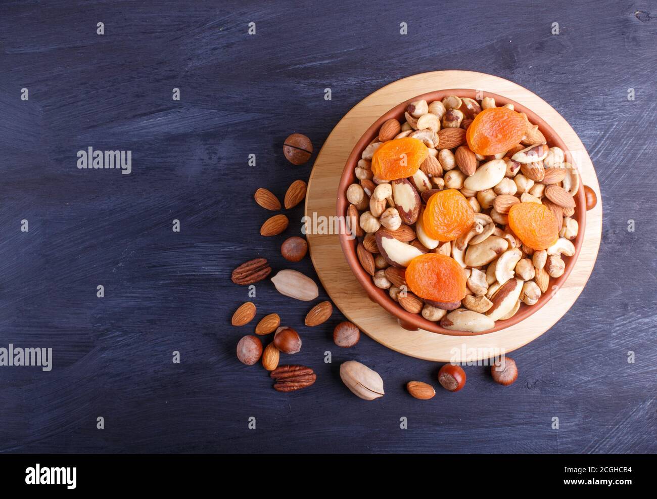Mixed different kinds of nuts in ceramic bowl on black wooden