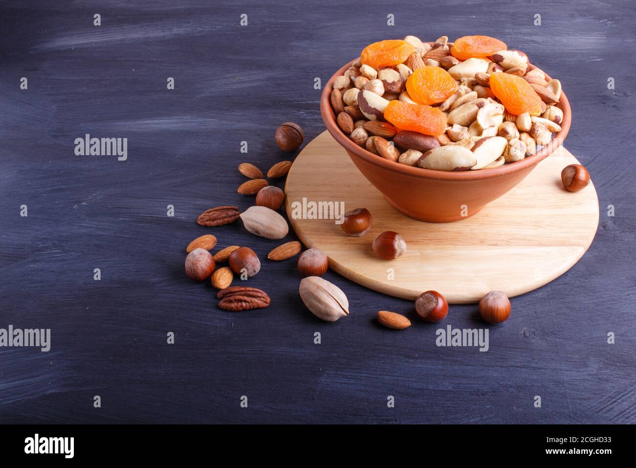 Mixed different kinds of nuts in ceramic bowl on black wooden