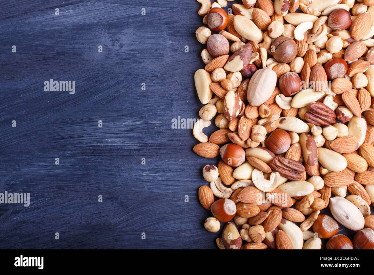 Mixed different kinds of nuts on black wooden background. hazelnut