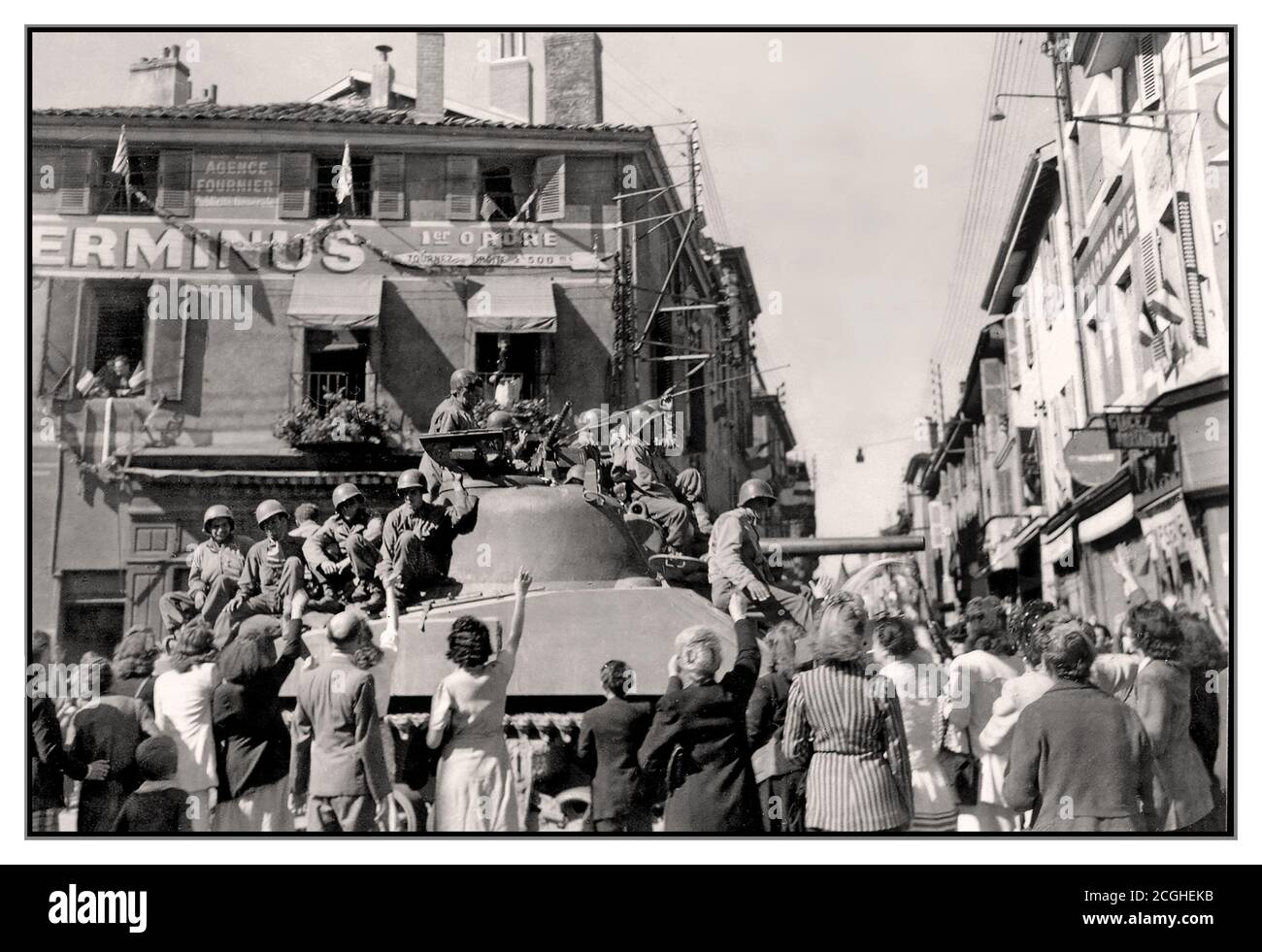 WW2 France Liberation in a provincial French town, after D-Day with the rapidly advancing American 45th Infantry Division. Local villagers wave and happily crowd around their US Army liberators who are sitting on their American tank enjoying the enthusiastic welcome. September 1944. World War II Second World War Stock Photo