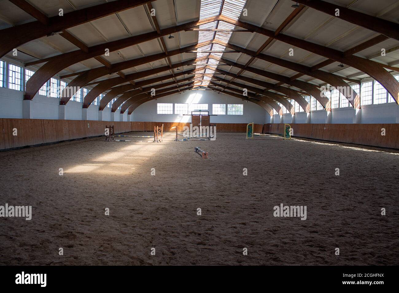 A light-flooded riding arena with some jumping obstacles. Stock Photo