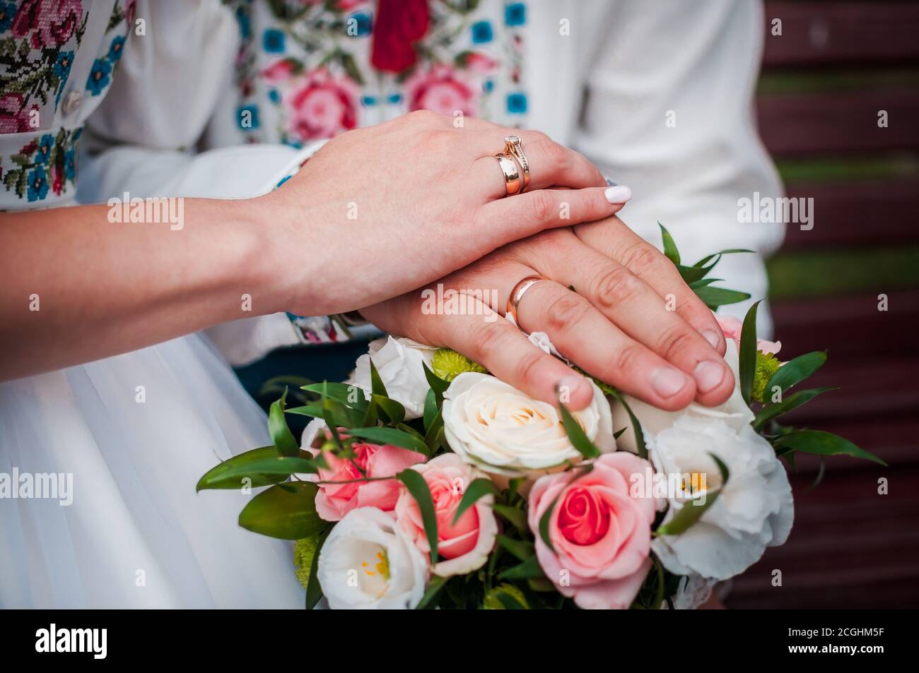 hands of newlyweds with wedding rings on a wedding bouquet with white and pink roses Stock Photo
