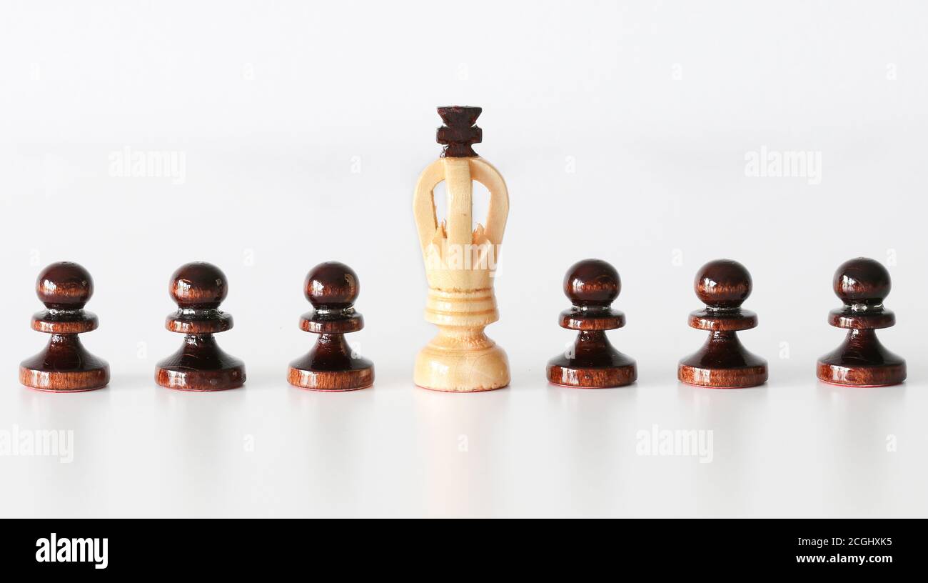 Row of black pawn chess pieces with white king in the middle on white background - stand out of the crowd concept Stock Photo