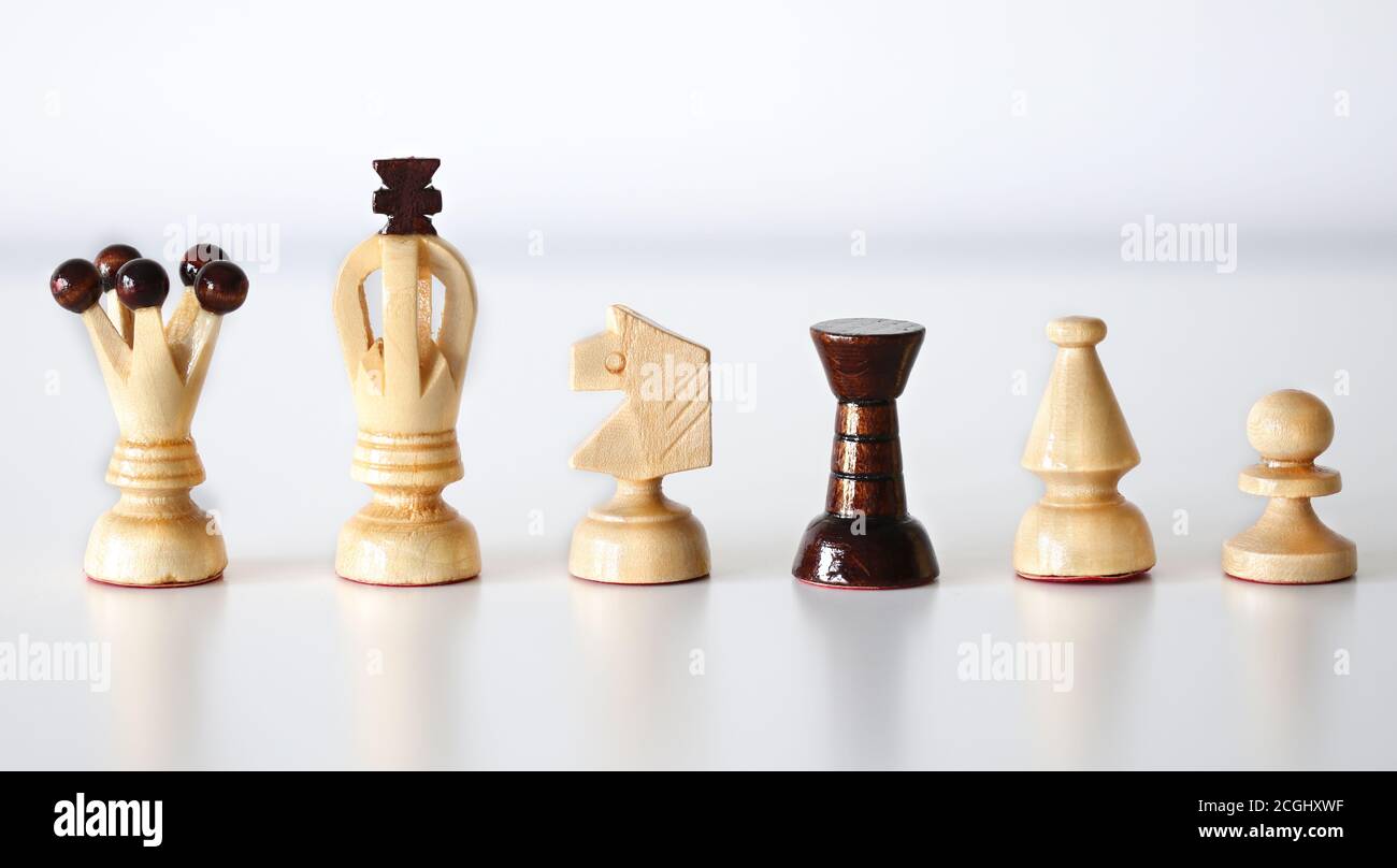 All six chess pieces in a row on white background, black rook amid white pieces as stand out of the crowd concept Stock Photo