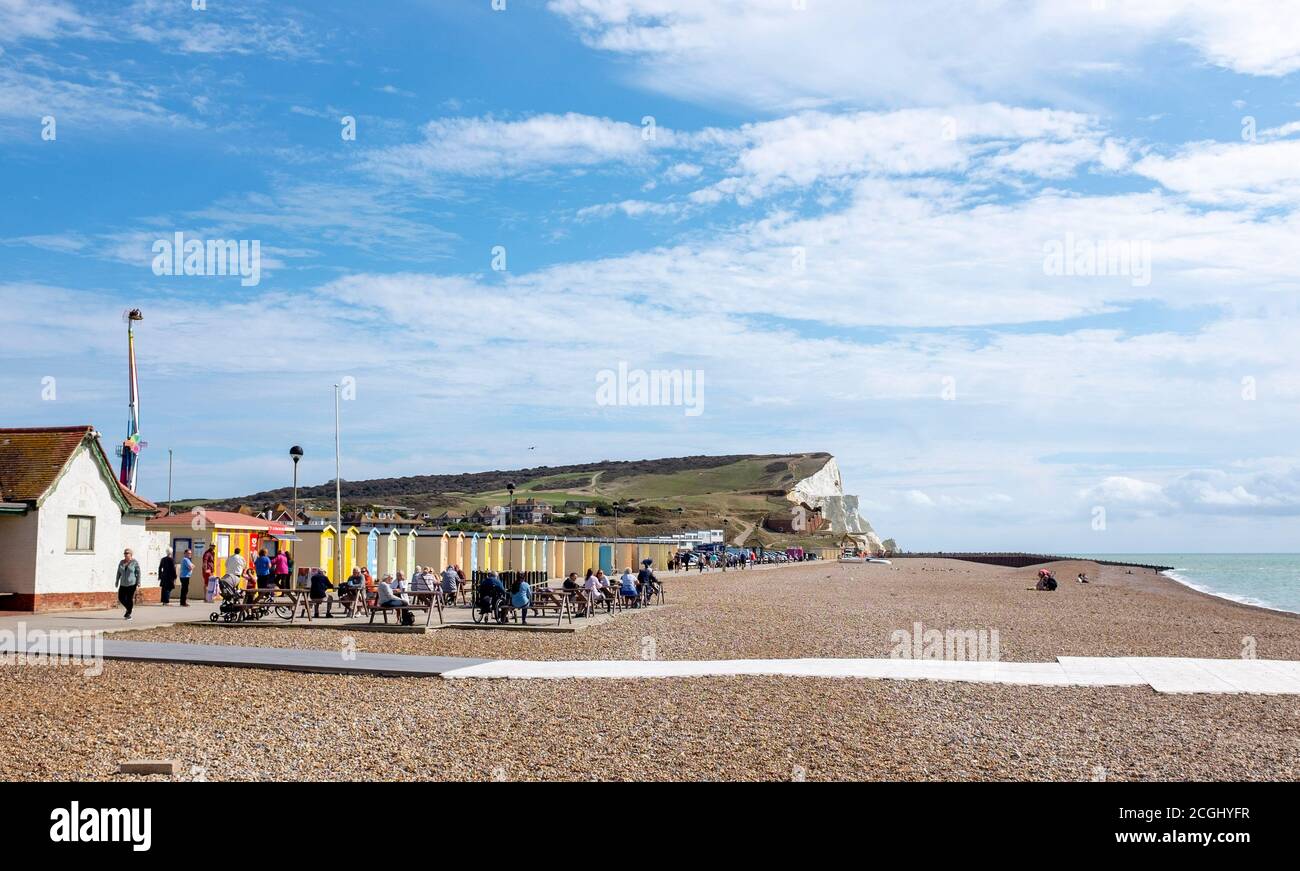 Seaford East Sussex town views and landscapes - Colourful beach huts on the seafront and cafe with Seaford Head cliffs behind  Photograph taken by Sim Stock Photo