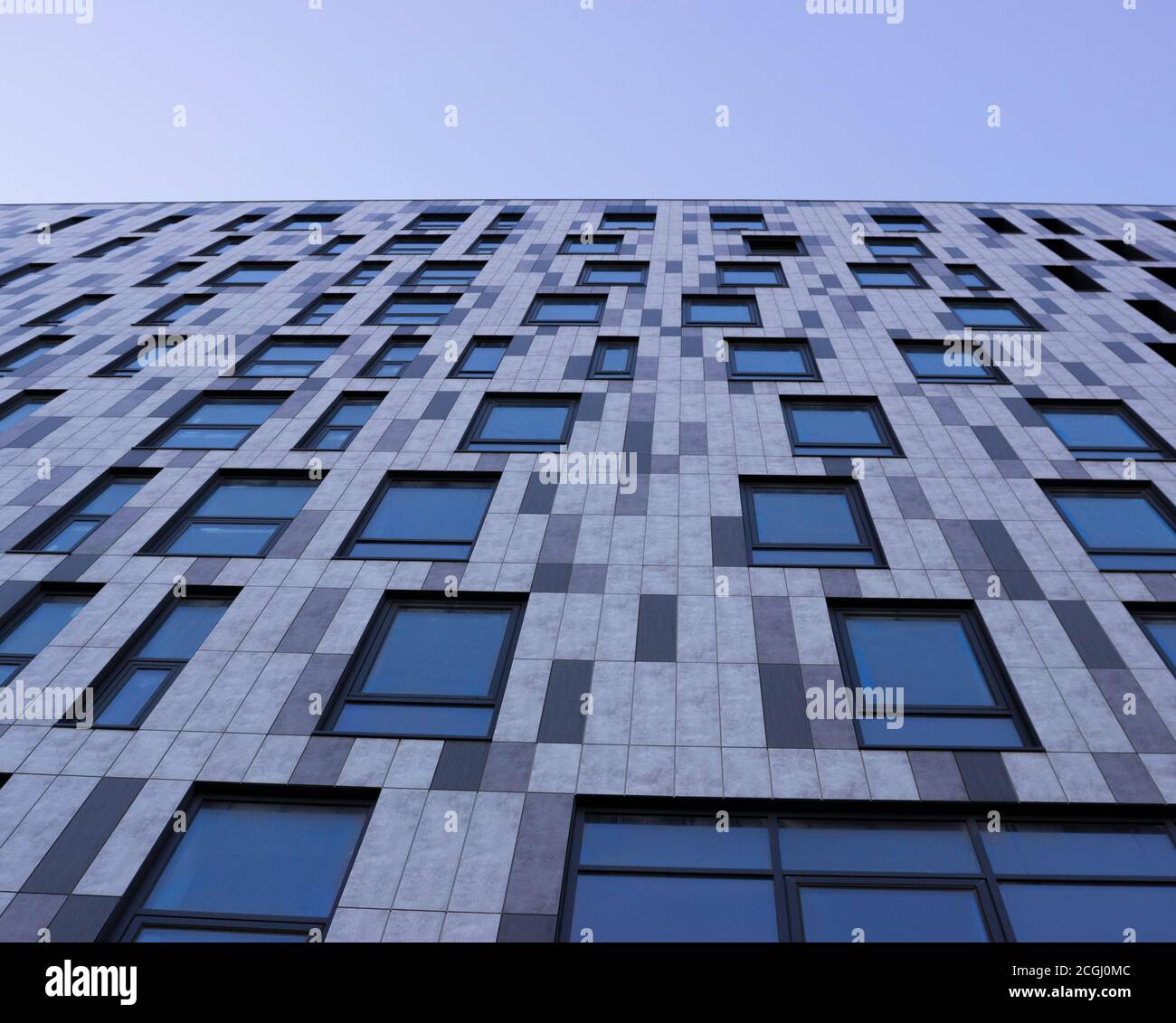 Grey building with Windows, view from below, blue sky. Graphically. Stock Photo