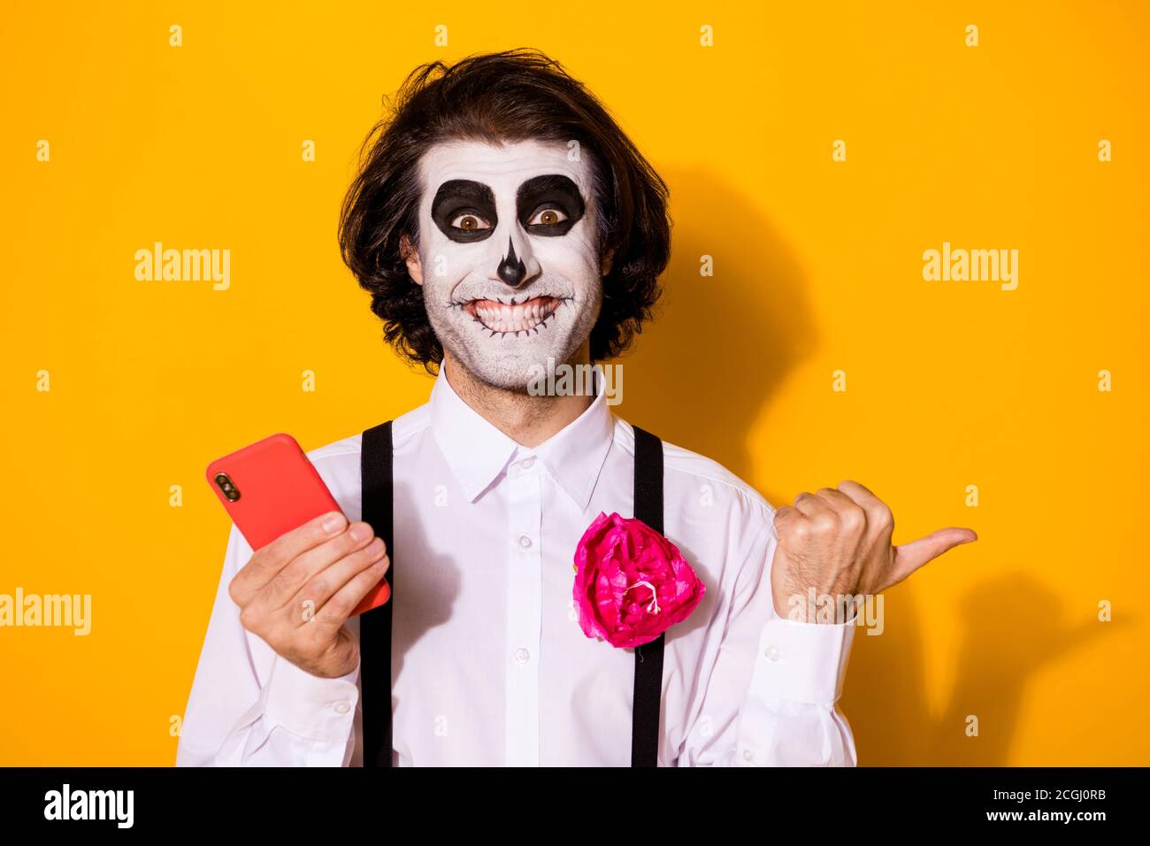 Close-up portrait of his he nice handsome creepy spooky cheerful glad guy using gadget app 5g demonstrating copy space advert calavera isolated bright Stock Photo