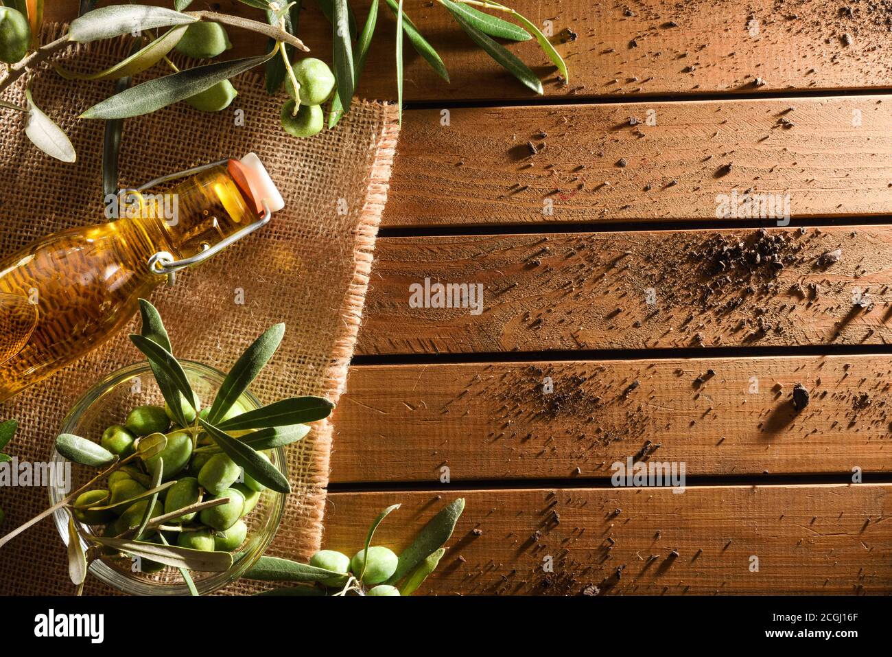 Glass bottle with olive oil on wooden table with branches and olives ...