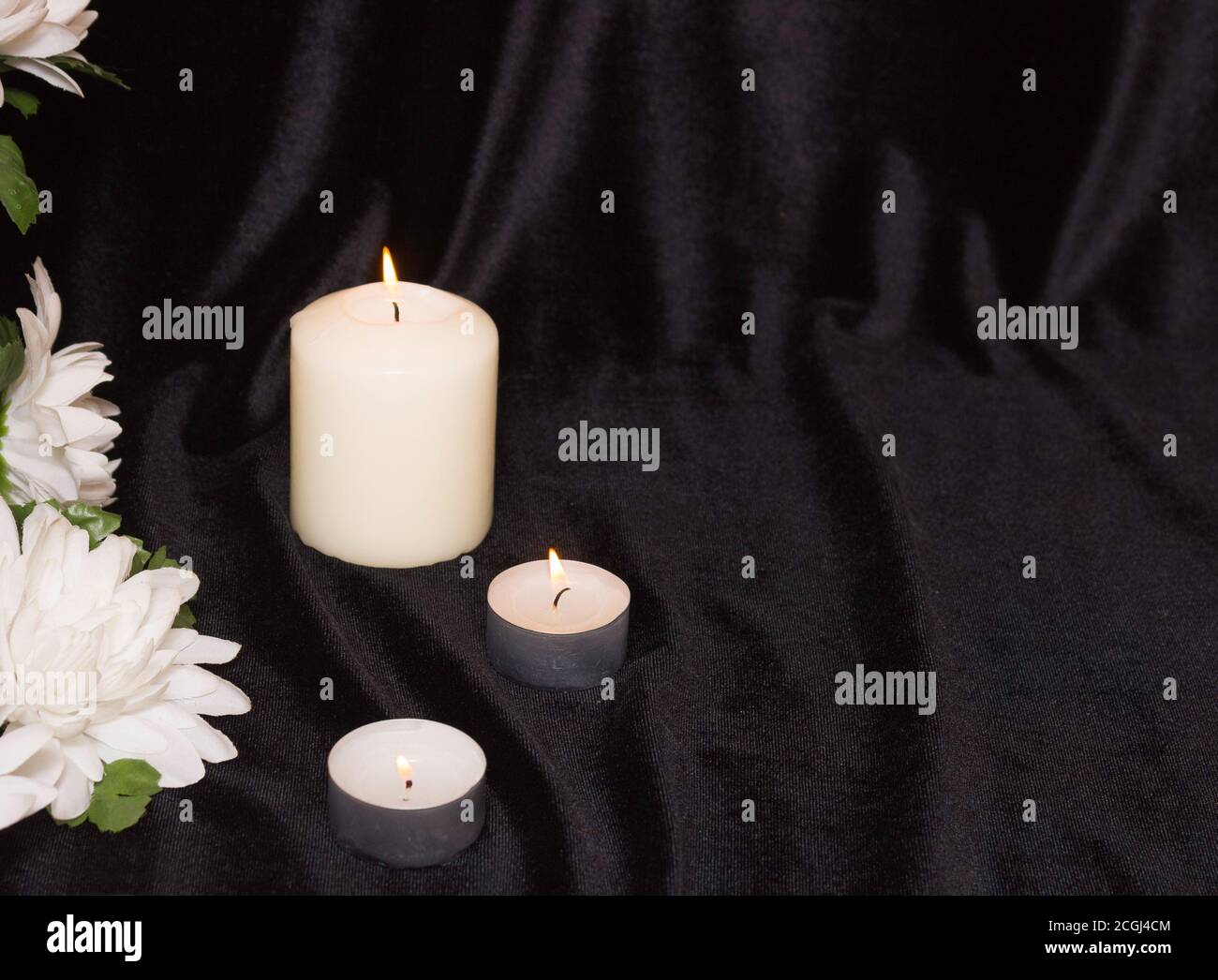 The concept of funeral service. Candles and white flowers on a black  background. Free space for text Stock Photo - Alamy