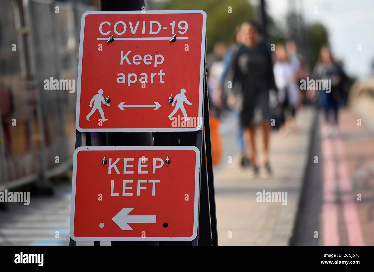 Pedestrians walk near public health signs, whilst the reproduction 'R' number of COVID-19 infections in the United Kingdom has risen and may be above 1, the Government Office for Science said on Friday, indicating a risk that the overall epidemic is growing, London, Britain, September 11, 2020. REUTERS/Toby Melville Stock Photo