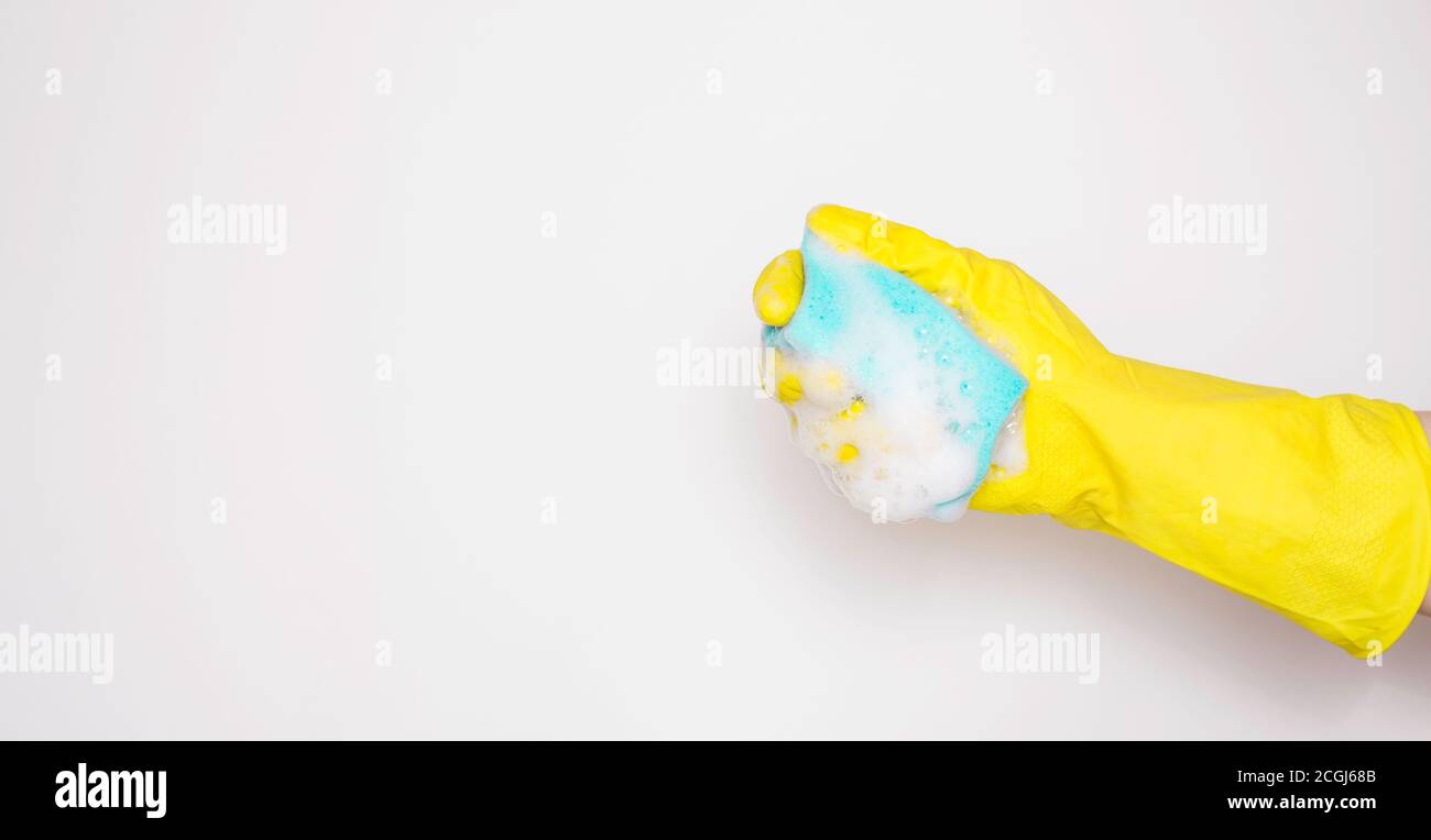 Hand in an yellow rubber glove with an blue sponge and foam on a white ...