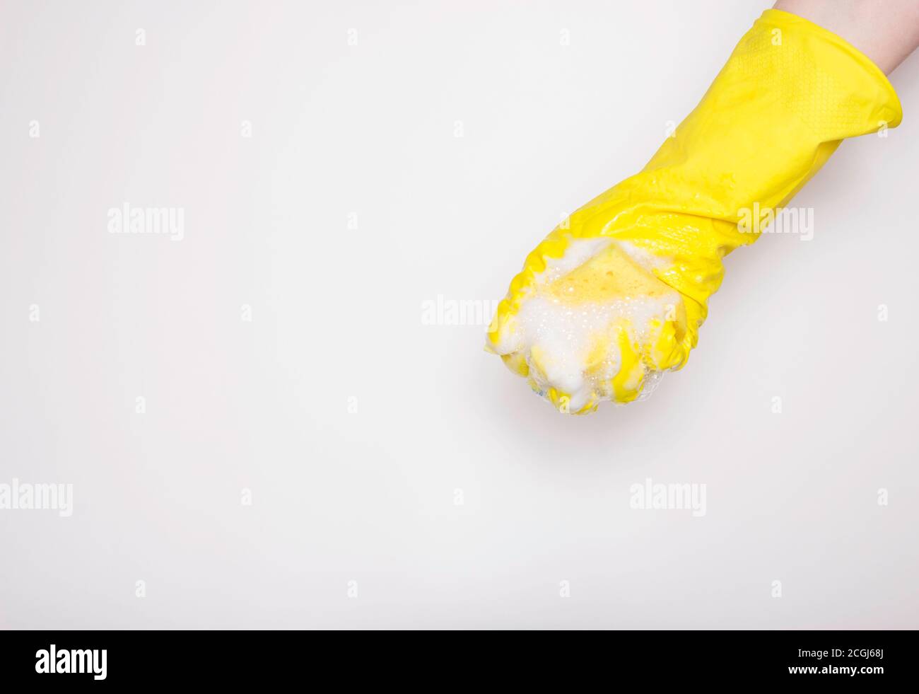 Hand in an yellow rubber glove with an yellow sponge and foam on a ...