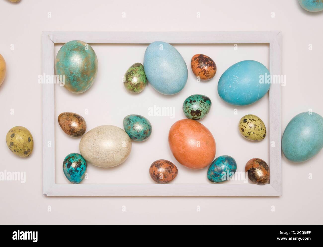 Colored Easter eggs in a wooden white frame on a white background. Stock Photo