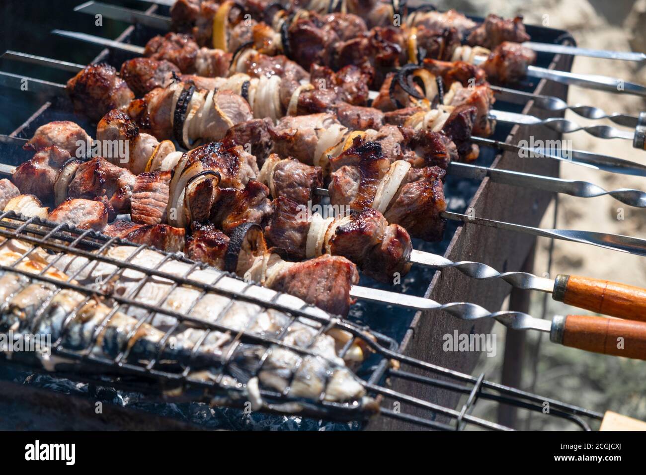 Fish and pork shish kebab roasting on a brazier strung on a skewer Stock Photo