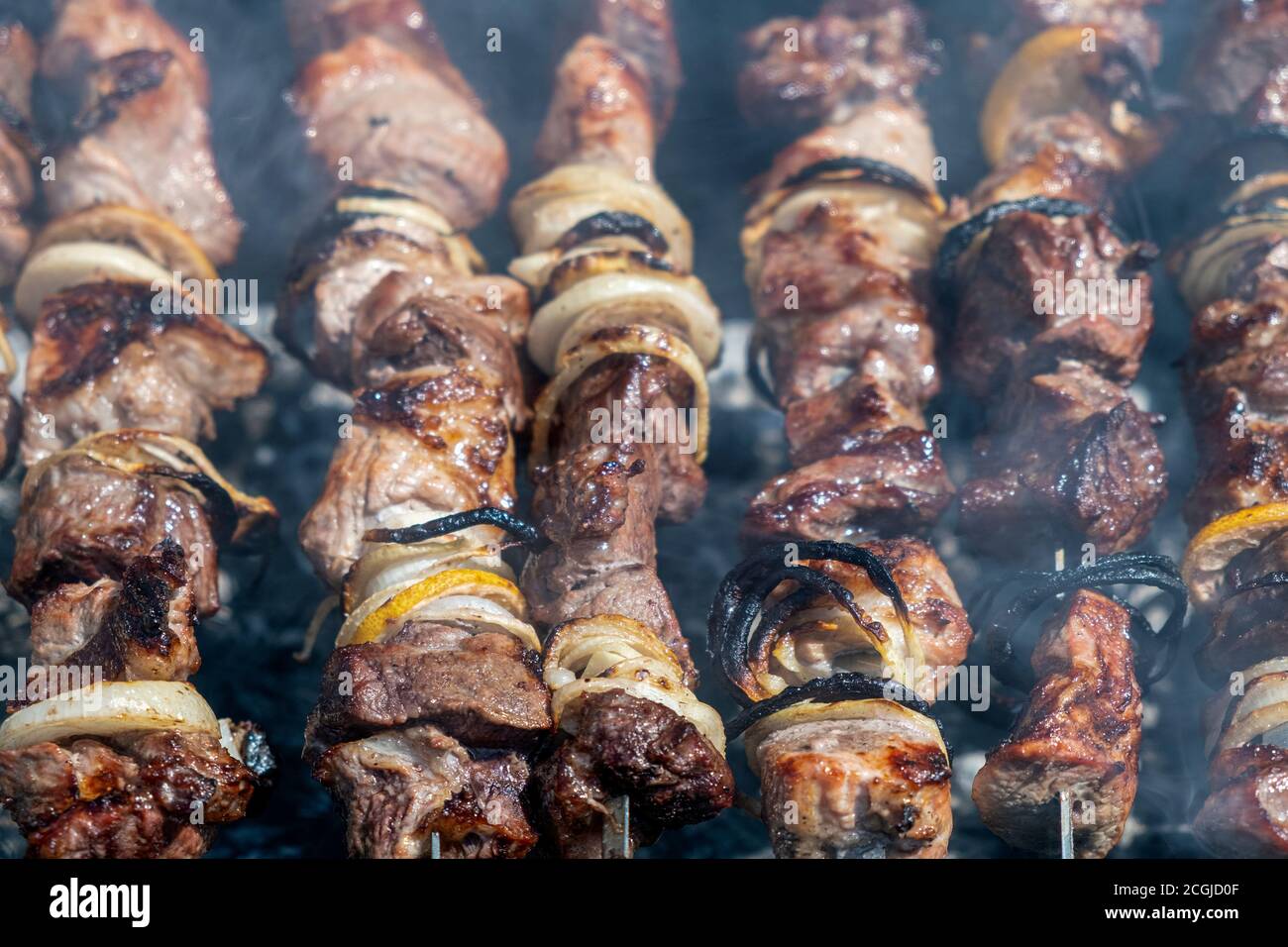 Pork shish kebab roasting on a brazier strung on a skewer, top view Stock Photo