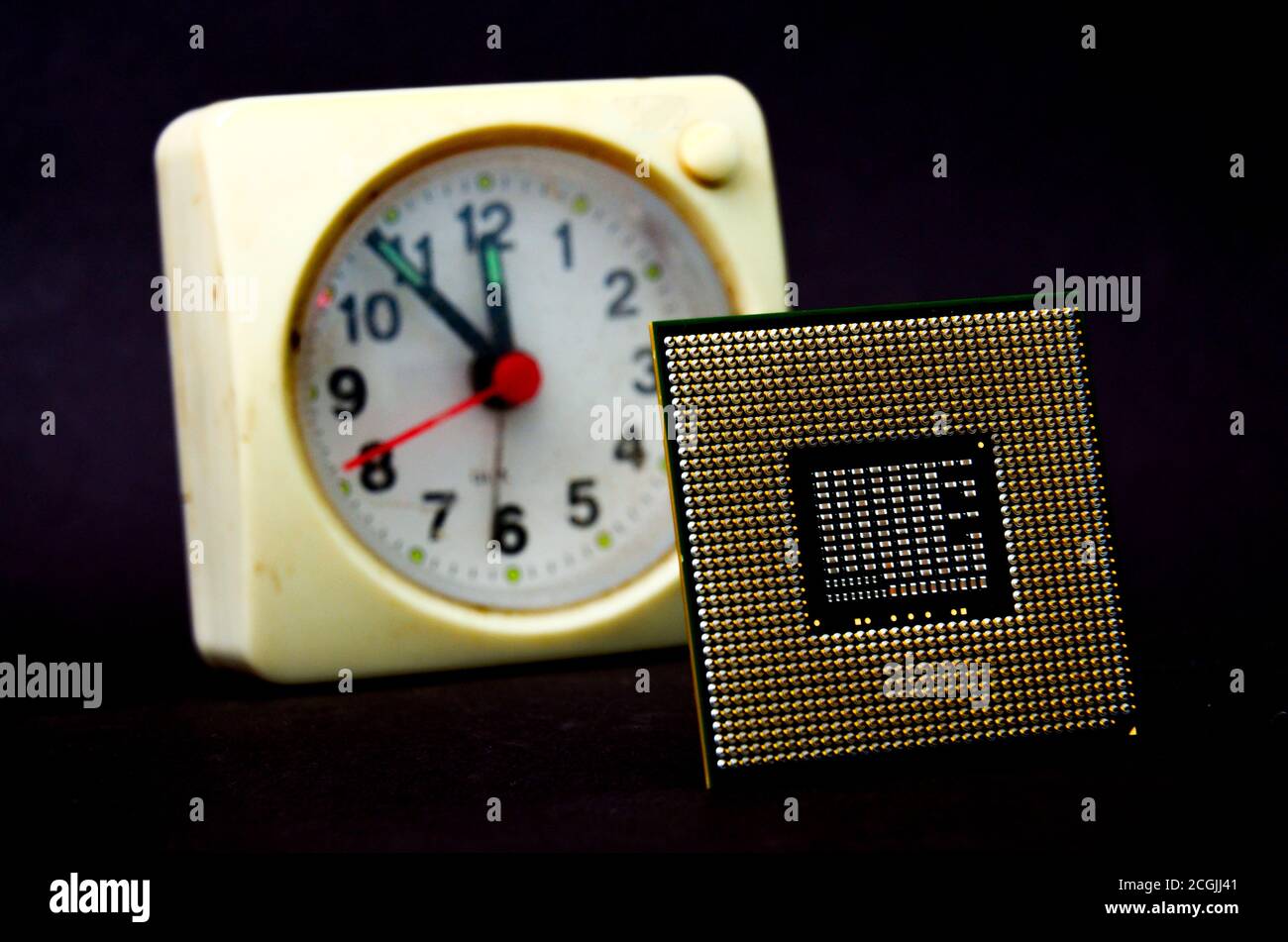 The computer processor on a dark background and vintage clock. Stock Photo