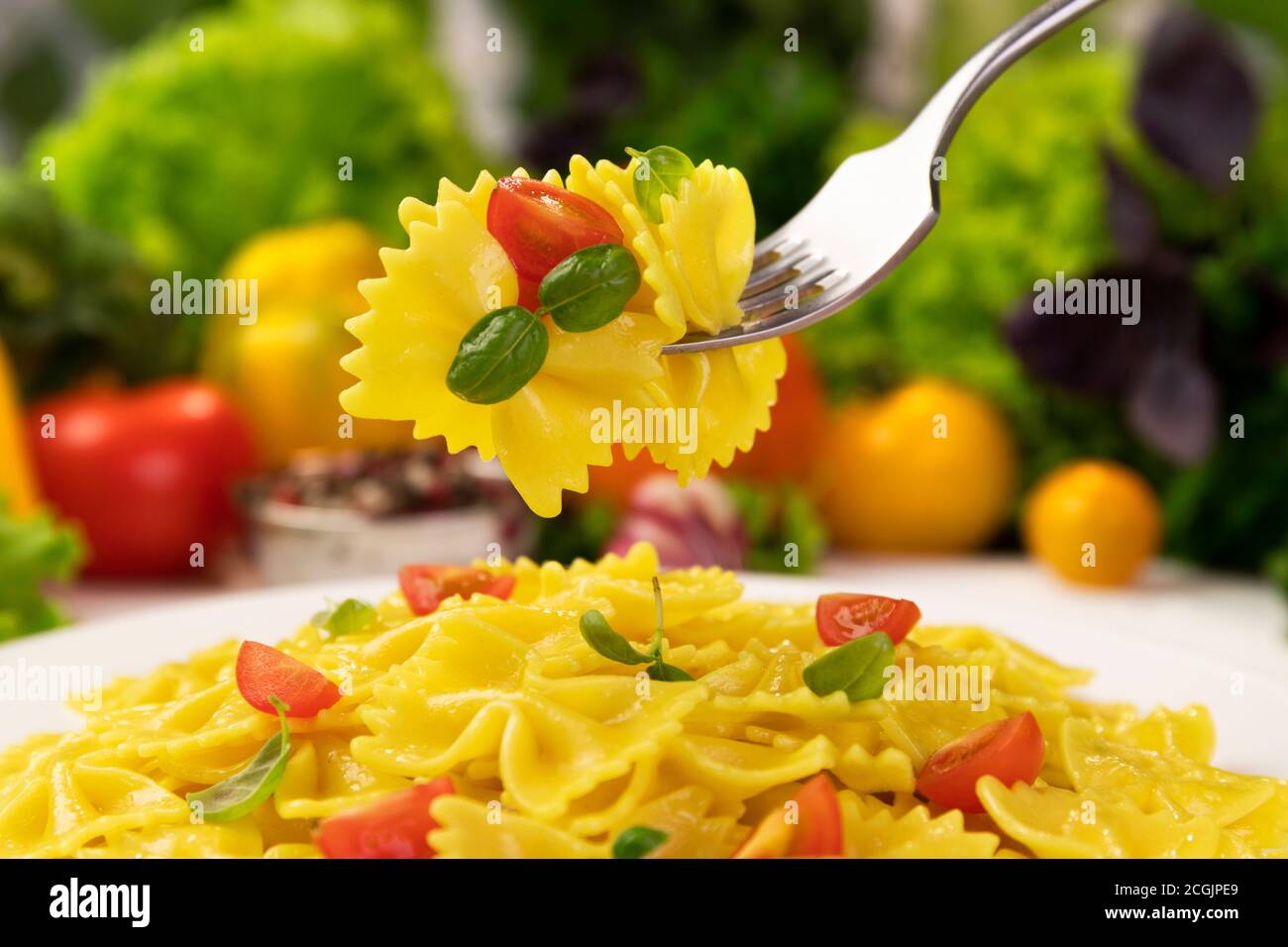 Plate of italian pasta, farfalle on fork with tomatoes and basil Stock Photo