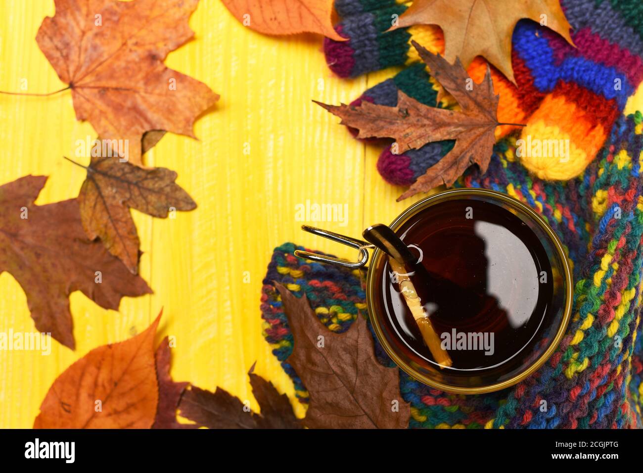 Autumn leaves, hot steaming cup of tea and a warm scarf on yellow ...