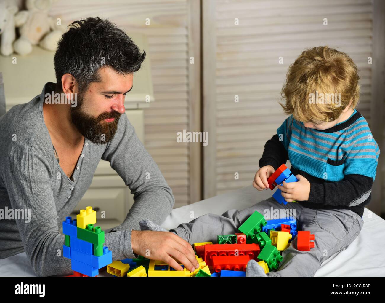 Dad and kid build of plastic blocks. Father and son with happy faces ...