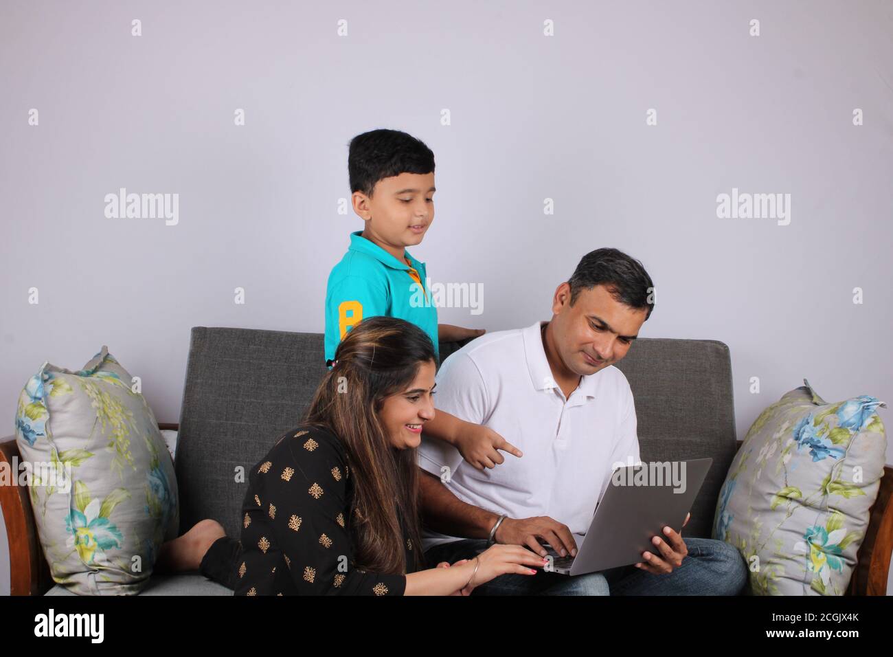 adorable young indian family using laptop at home. Stock Photo