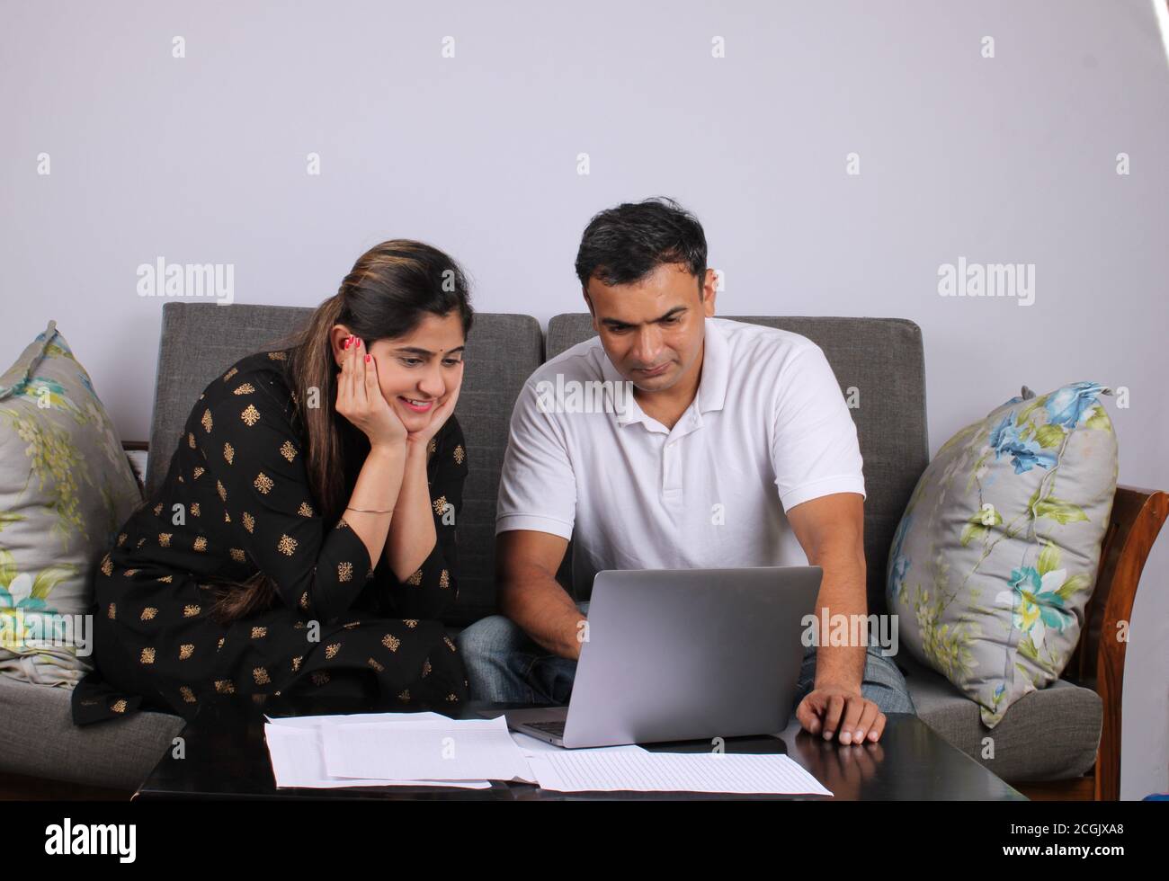 young Indian couple using the laptop sitting on a sofa Stock Photo - Alamy