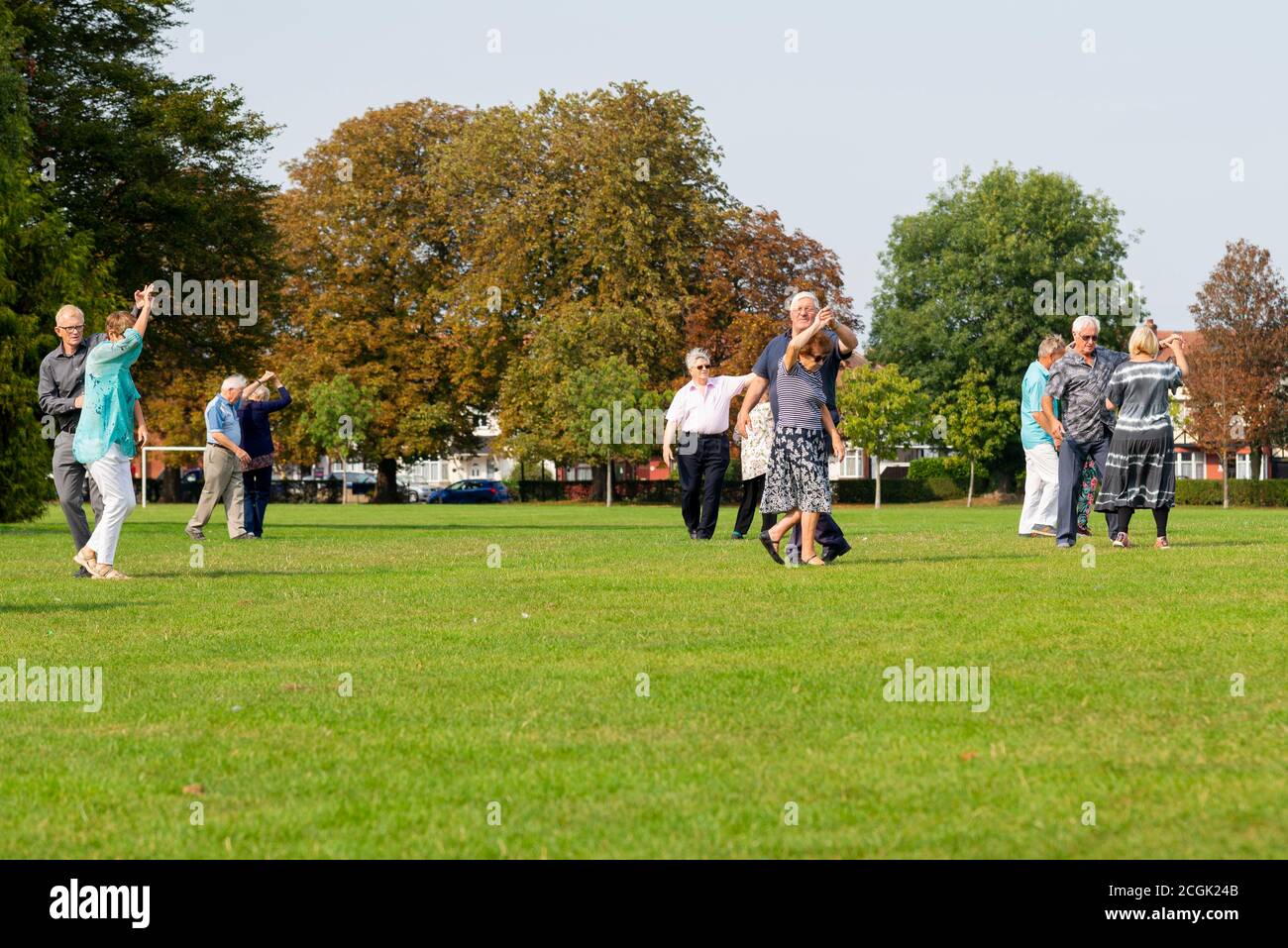 Senior couples dancing ballroom steps in the park. Elderly males and females dancing in hold in Priory Park, Southend on Sea, Essex, UK. Autumn Stock Photo