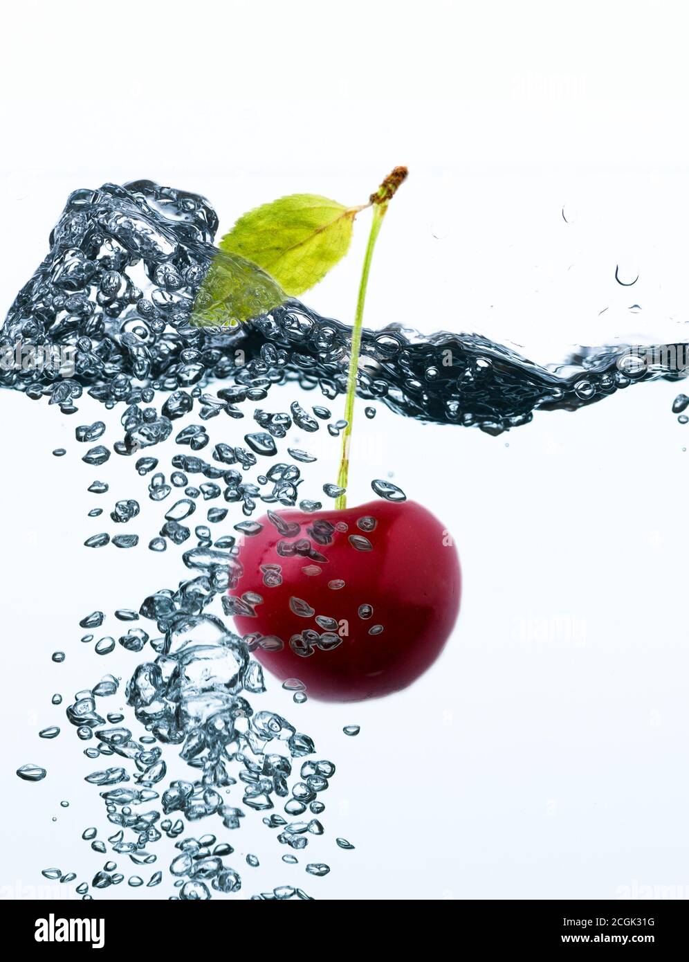 A cherry with stem and leaf underwater in sparkling water Stock Photo