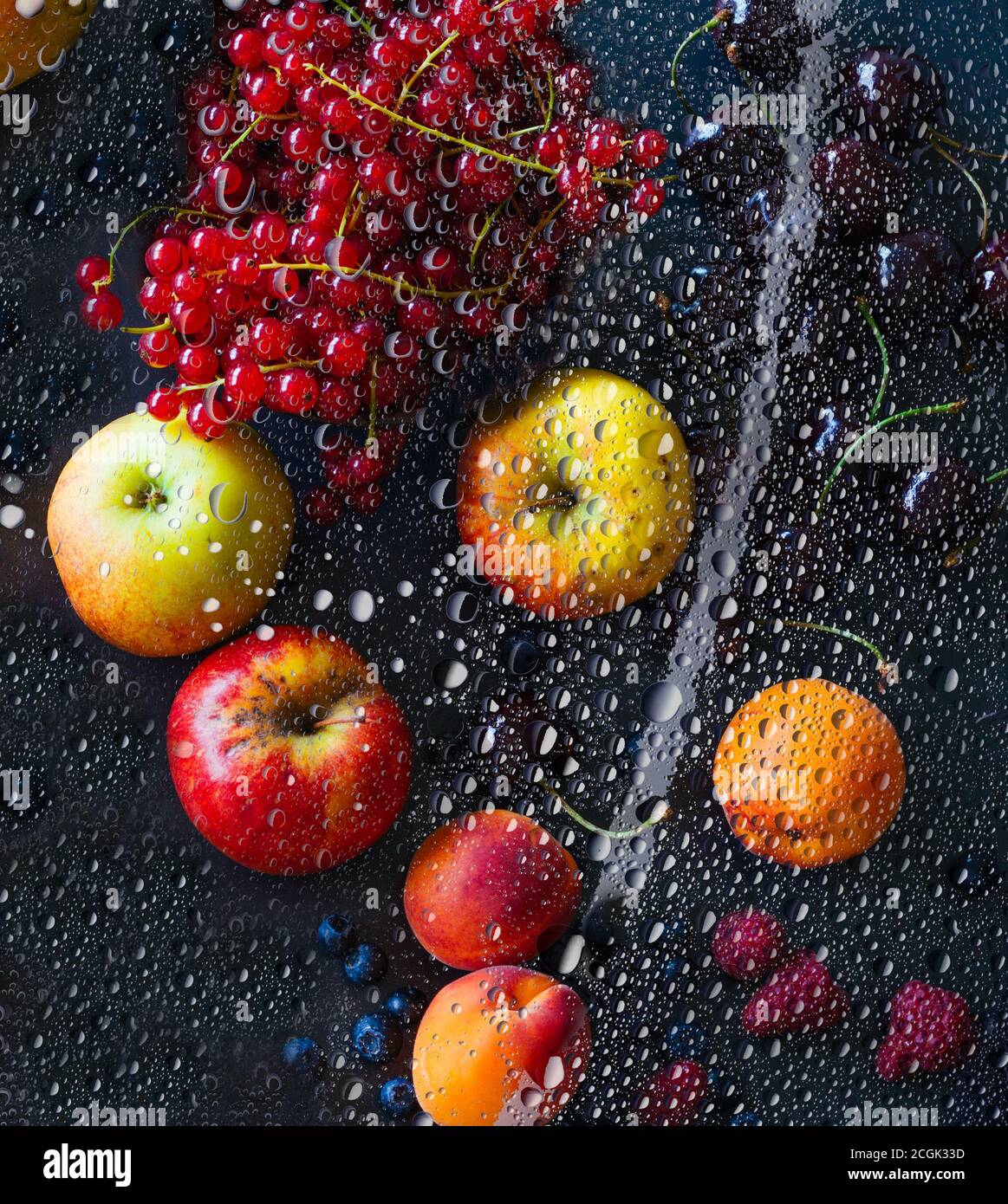 Fresh different fruits and berries, apple, apricot, currant, raspberry, chilled under dewed glass on black background Stock Photo