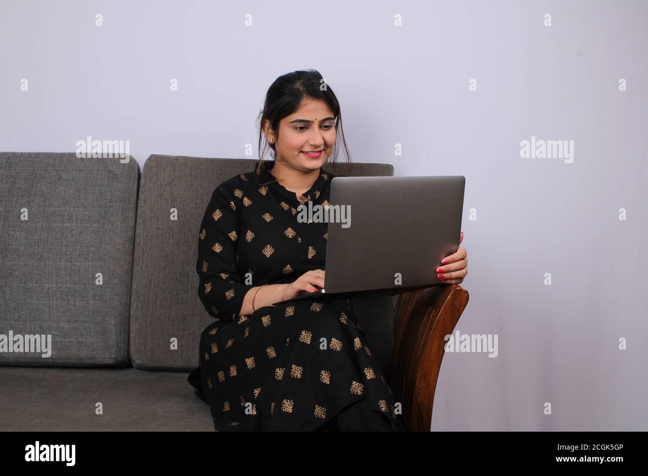 Young Indian woman or housewife working on laptop. Stock Photo