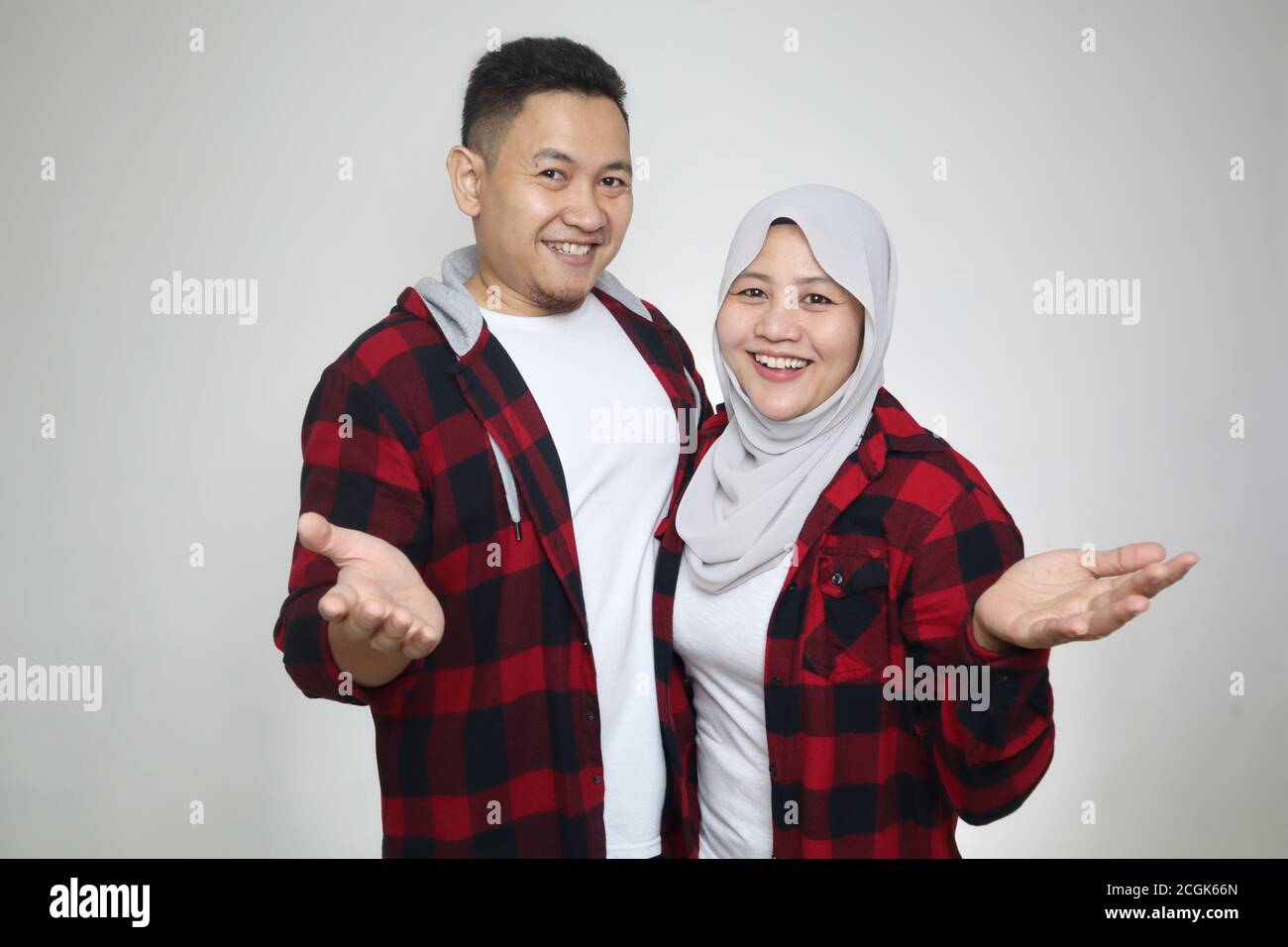 Beautiful happy Asian muslim couple wearing casual clothes smiling friendly offering handshake as greeting and welcoming Stock Photo