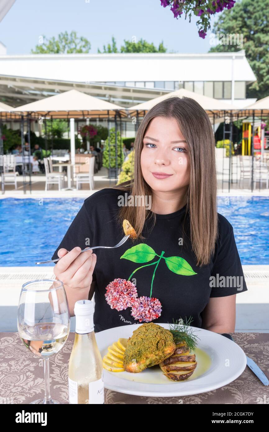 Woman eating main dish by the pool Stock Photo