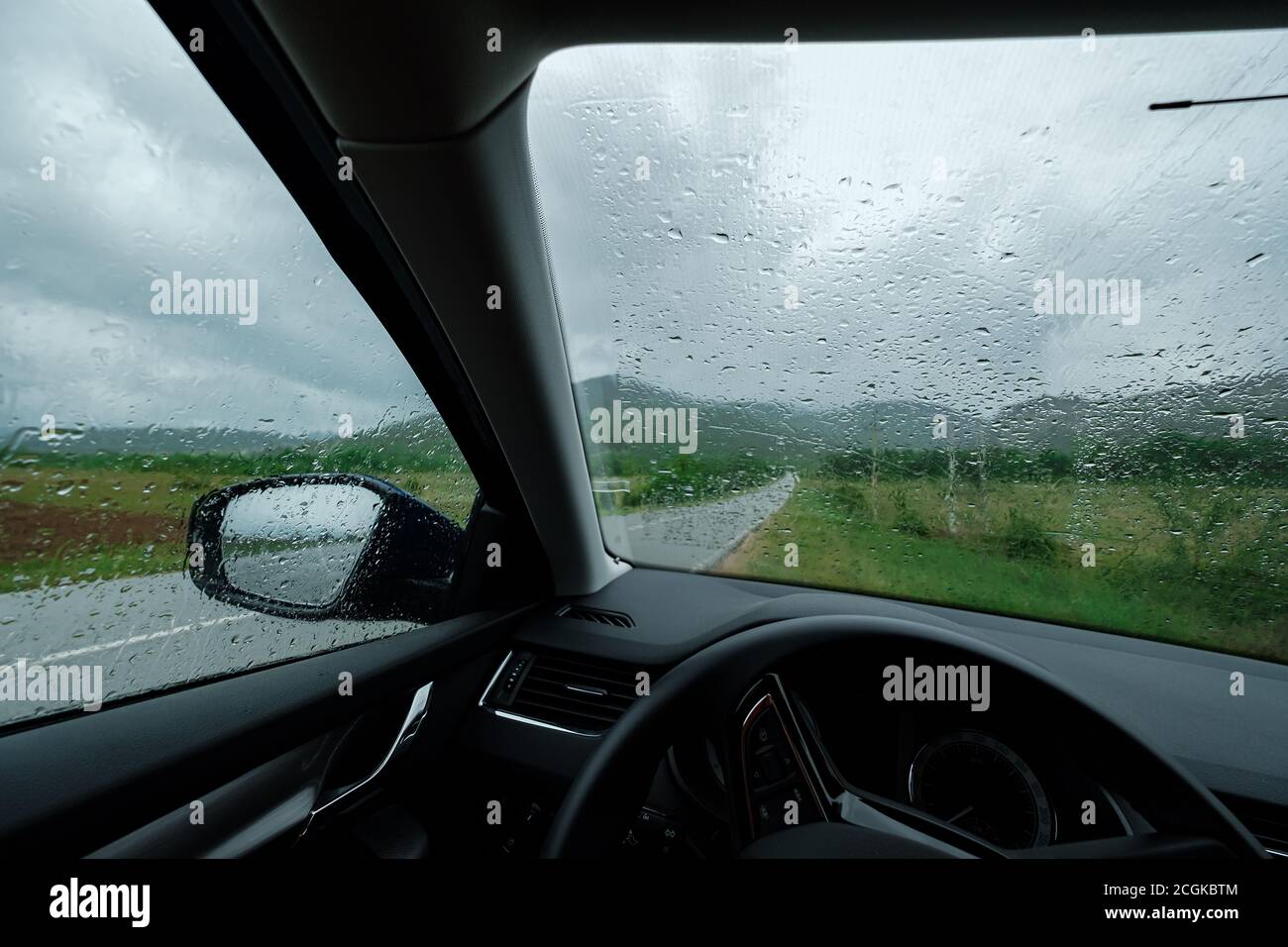 Driving car in the rain on wet road. Rainy weather through the car